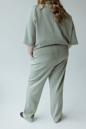 A person wearing an oversized, light green outfit stands with their back to the camera against a plain background, showcasing the Yesta Light as Air Trouser in Echeverria with its comfortable elastic waistband.