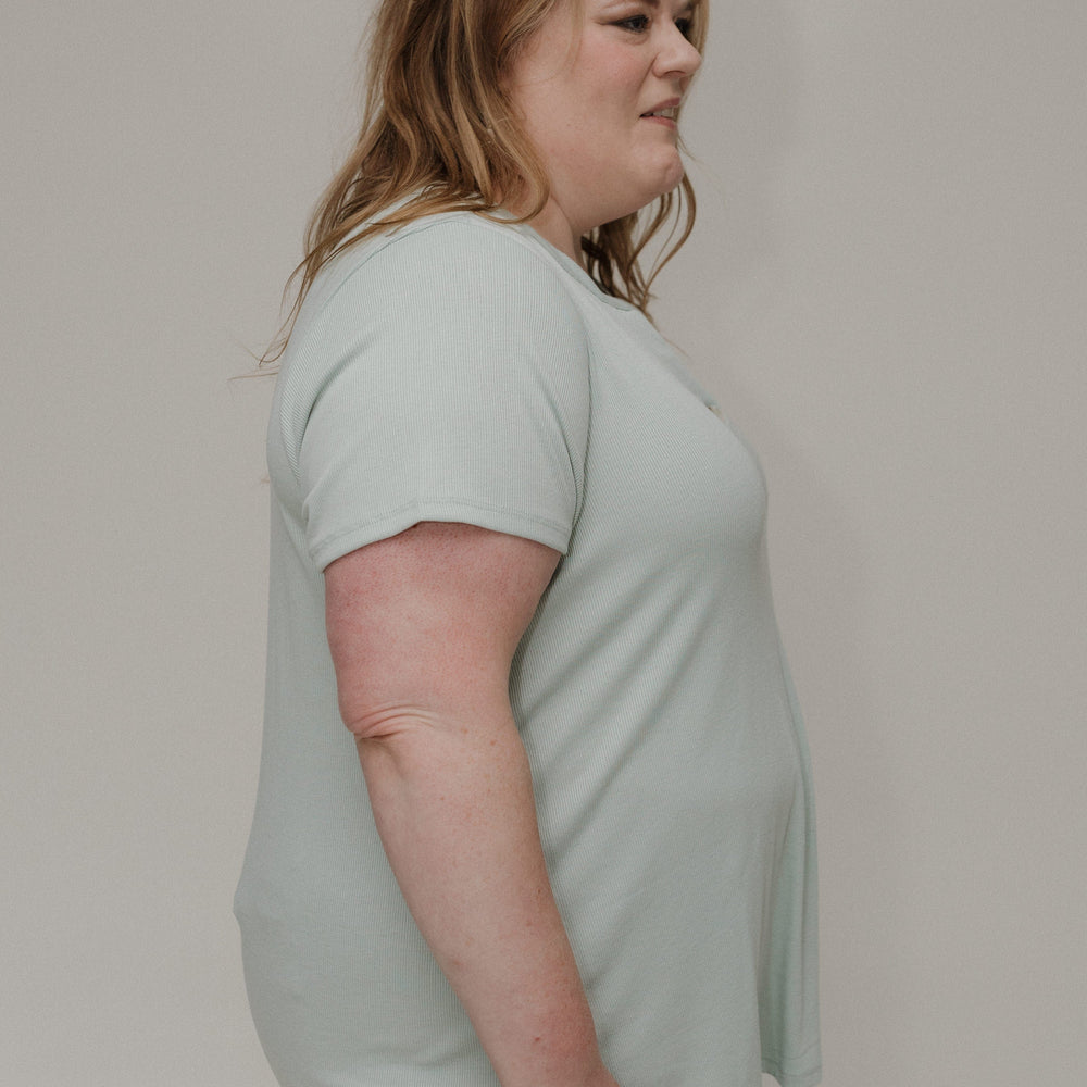 Woman wearing a light green t-shirt against a plain background