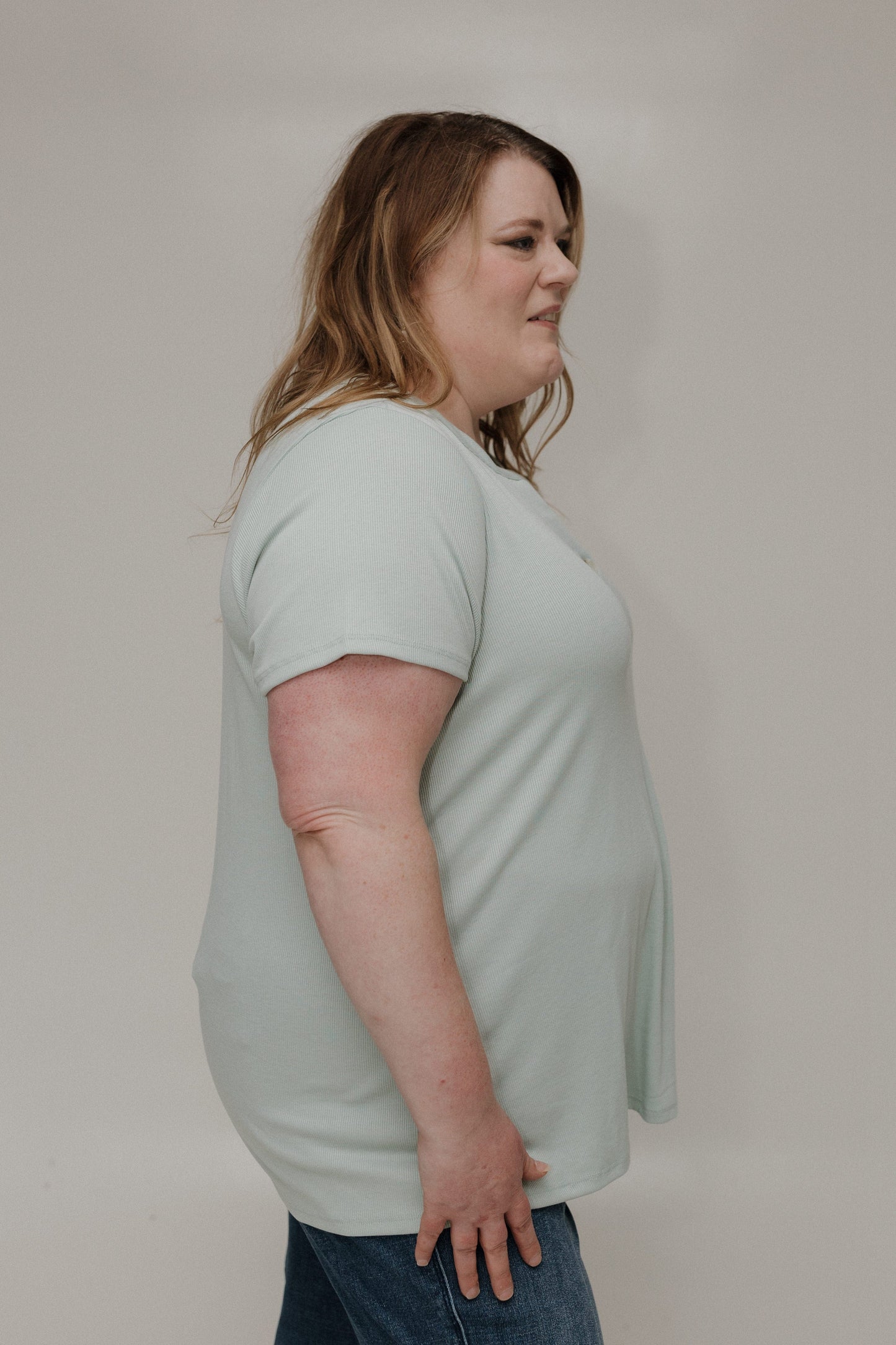 Woman wearing a light green t-shirt against a plain background