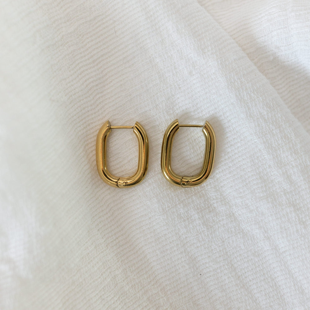 Gold hoop earrings on a white fabric background