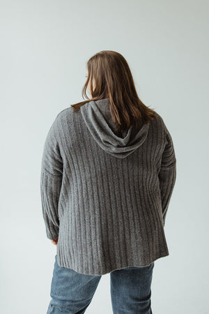 A person in a gray LINEAR ATHLEISURE HOODIE by Yesta and blue jeans stands with their back to the camera against a plain light background.