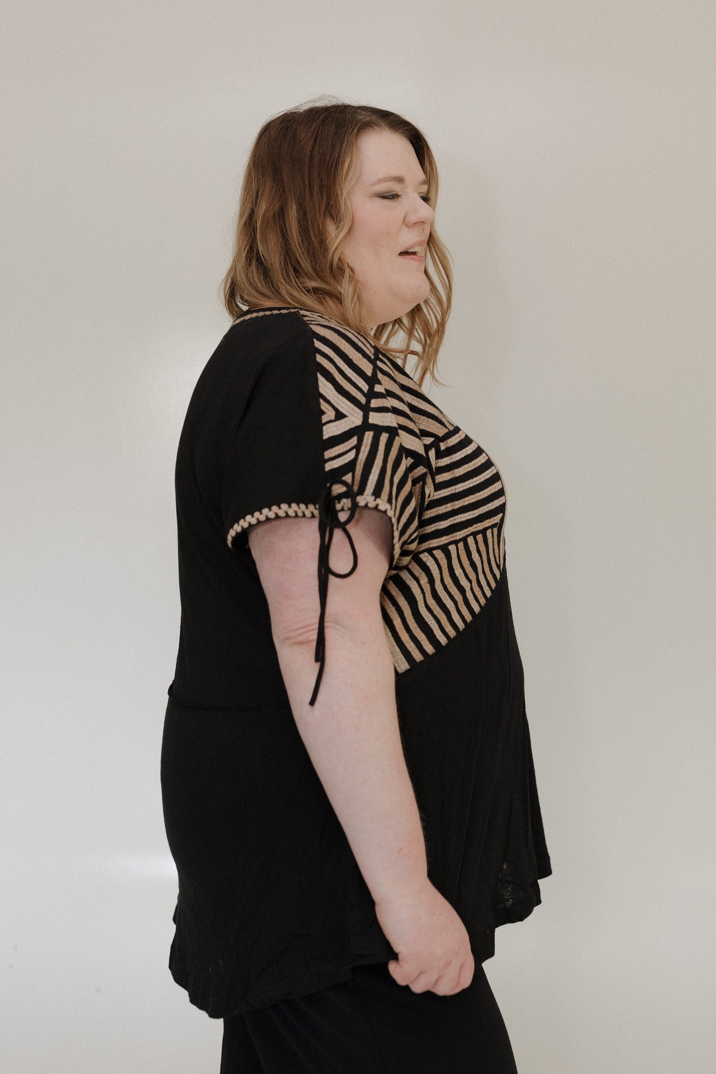 Woman wearing a black and beige patterned top against a plain background