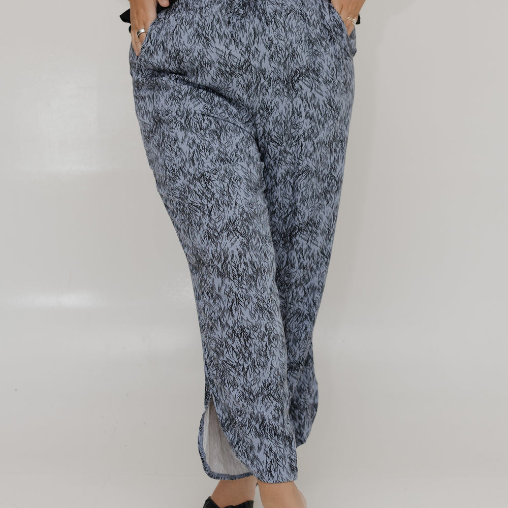 Person wearing a black top and blue marbled pants on a white background