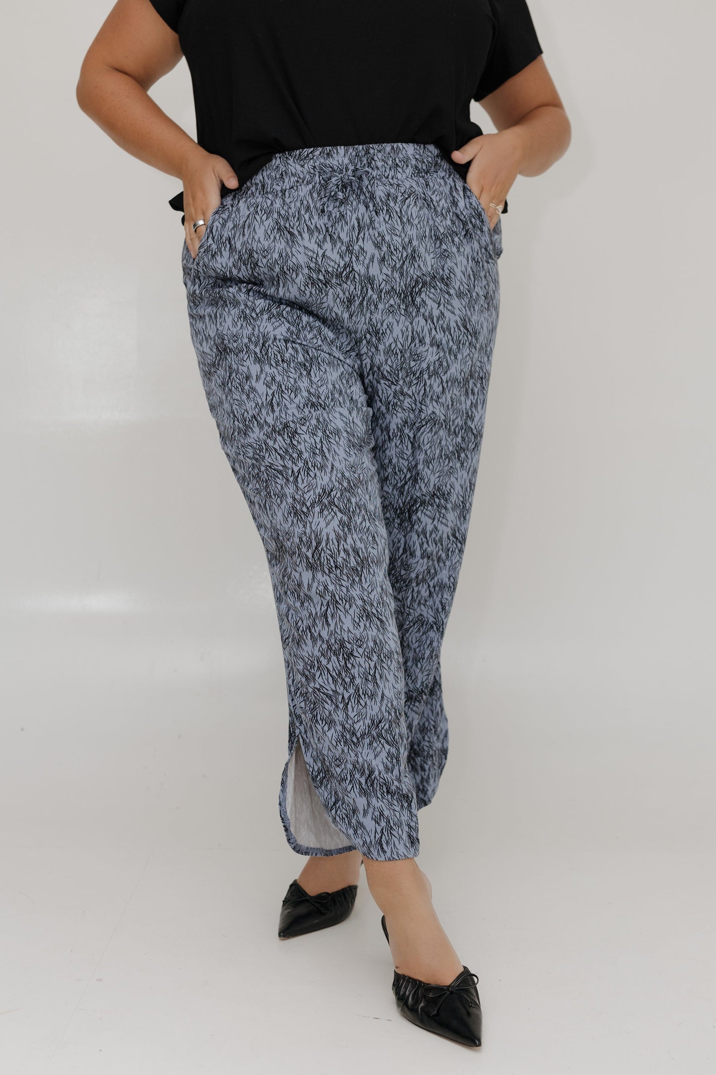 Person wearing a black top and blue marbled pants on a white background