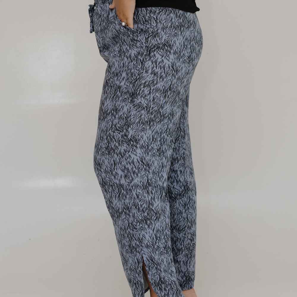 Person wearing a patterned skirt and black top on a plain background