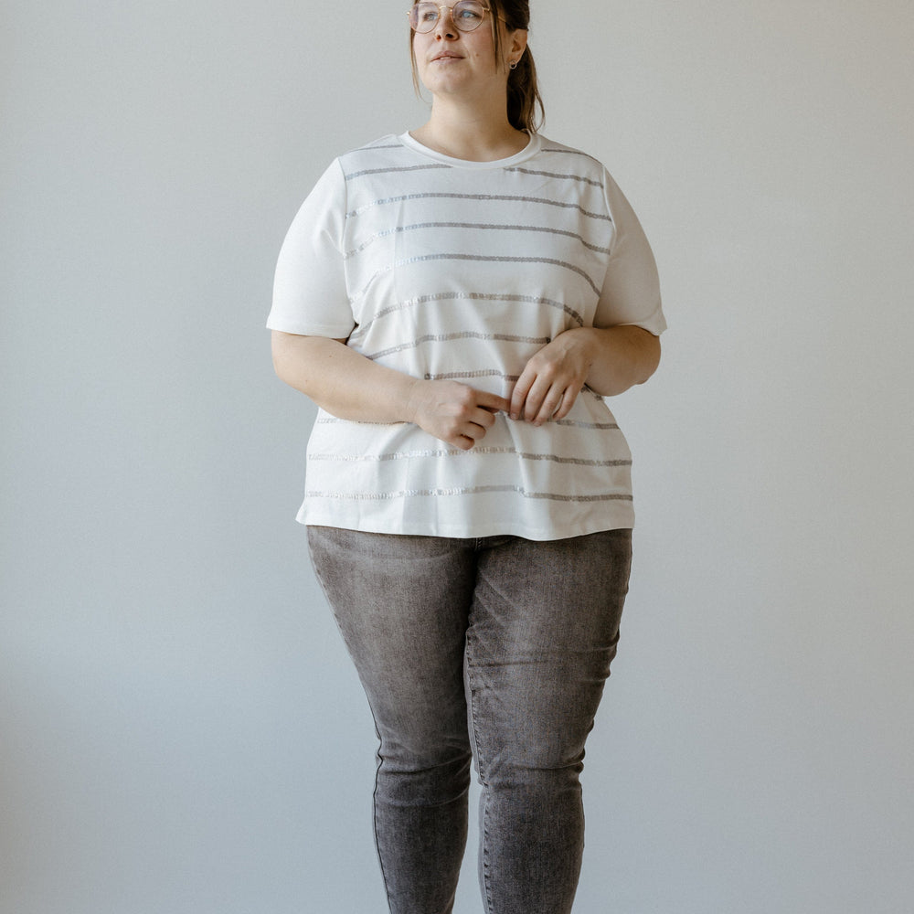 A person wearing a Sequin Stripe Tee and jeans, made from soft fabric, stands against a plain background.