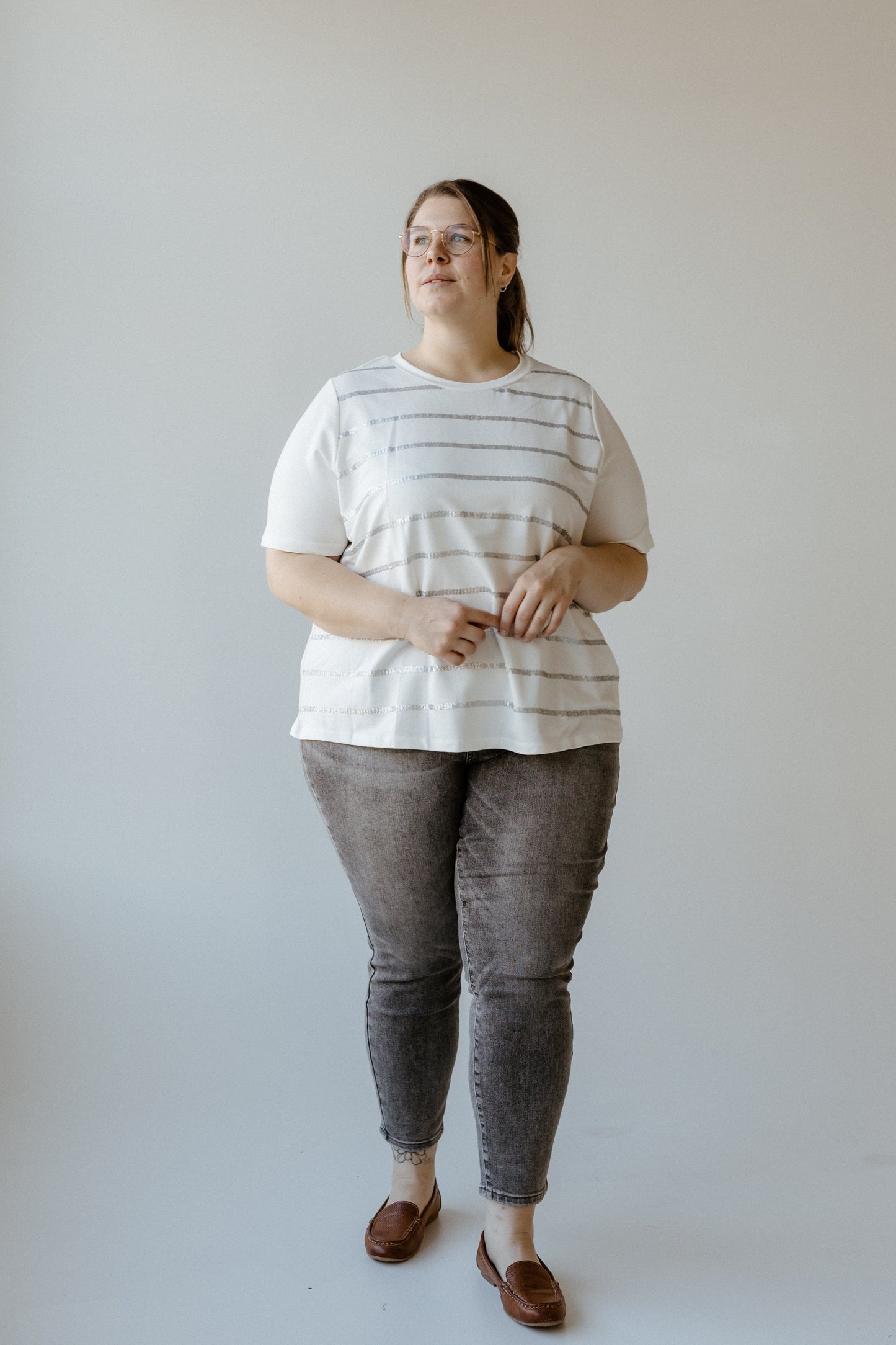 A person wearing a Sequin Stripe Tee and jeans, made from soft fabric, stands against a plain background.