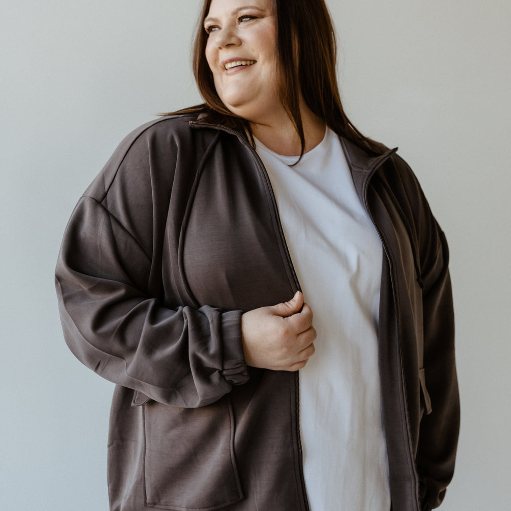 A stylish urbanite in a gray, light-as-air jacket and white shirt gazes to the side with a slight smile.