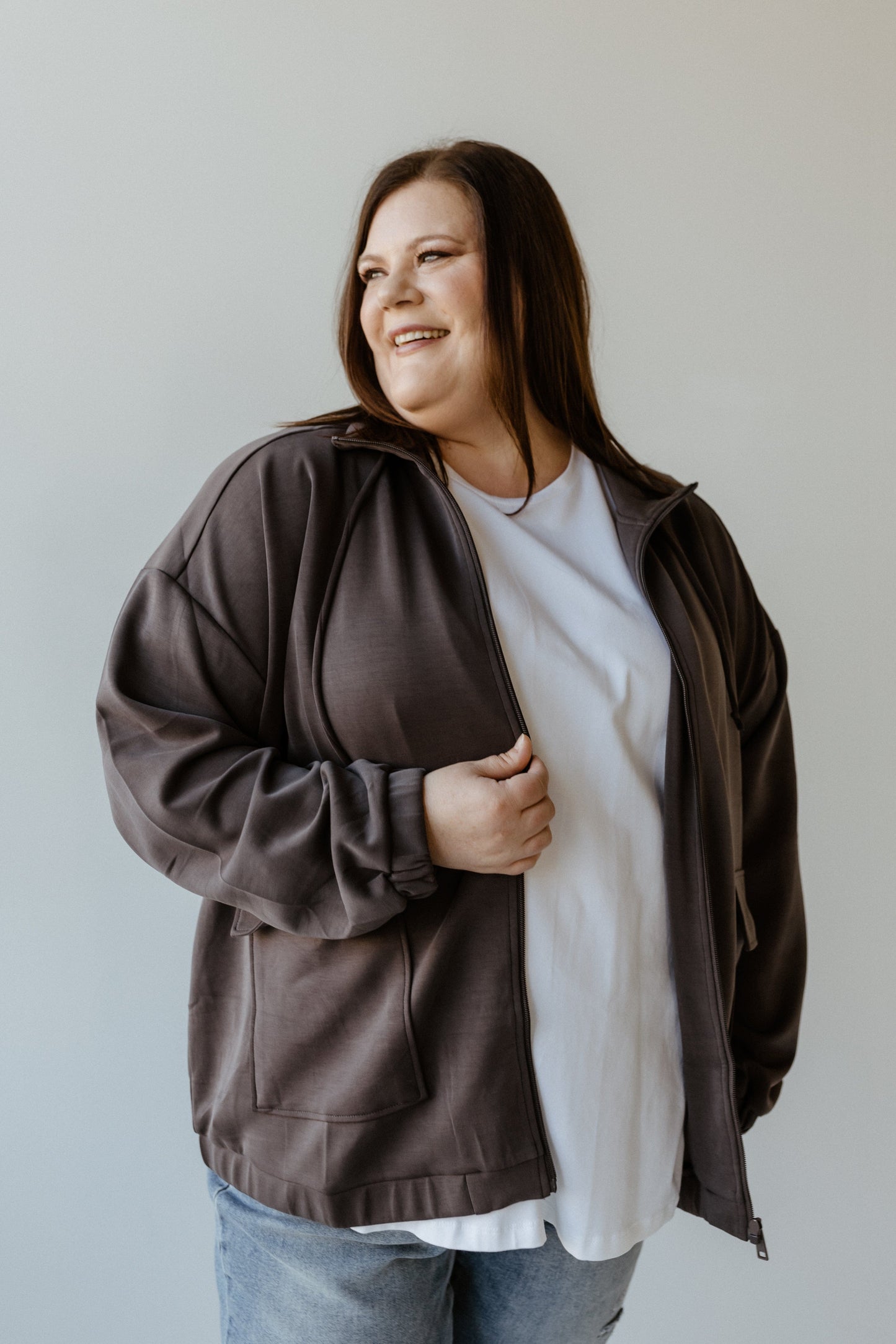 A stylish urbanite in a gray, light-as-air jacket and white shirt gazes to the side with a slight smile.