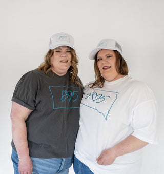 Two people wearing gray and white 605 South Dakota t-shirts with a blue outline of a state design on a plain background.