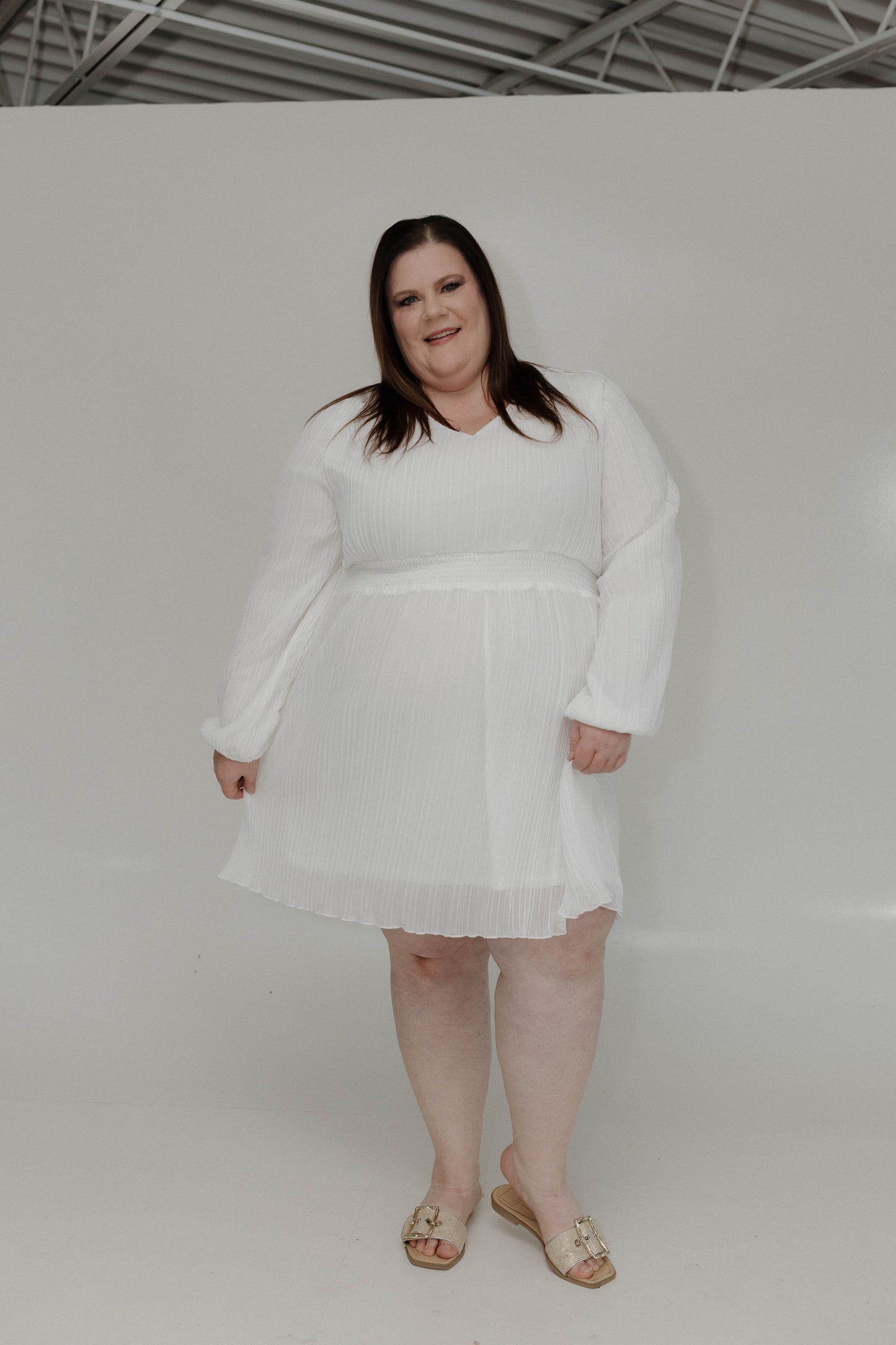 Woman wearing a white dress against a plain background