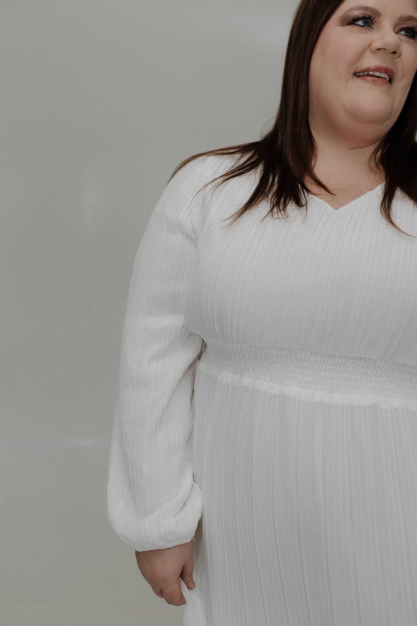 Woman wearing a white dress against a plain background
