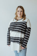 Rewritten sentence: Rear view of a person with long hair wearing the LONG-SLEEVE ROUND NECK TUNIC WITH STRIPE DETAIL IN CREAM from Love Marlow, paired with light blue jeans.