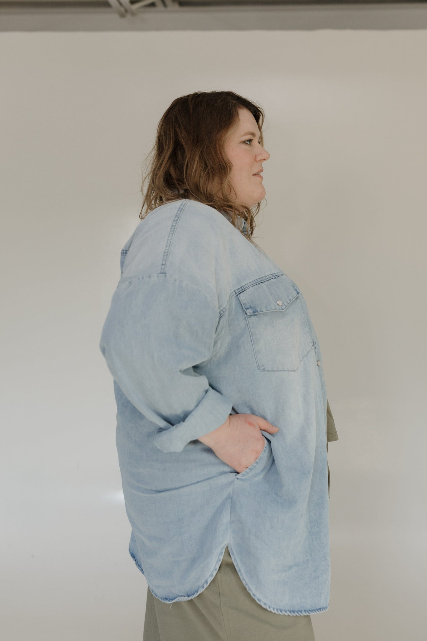 Person wearing a light blue denim jacket against a plain background