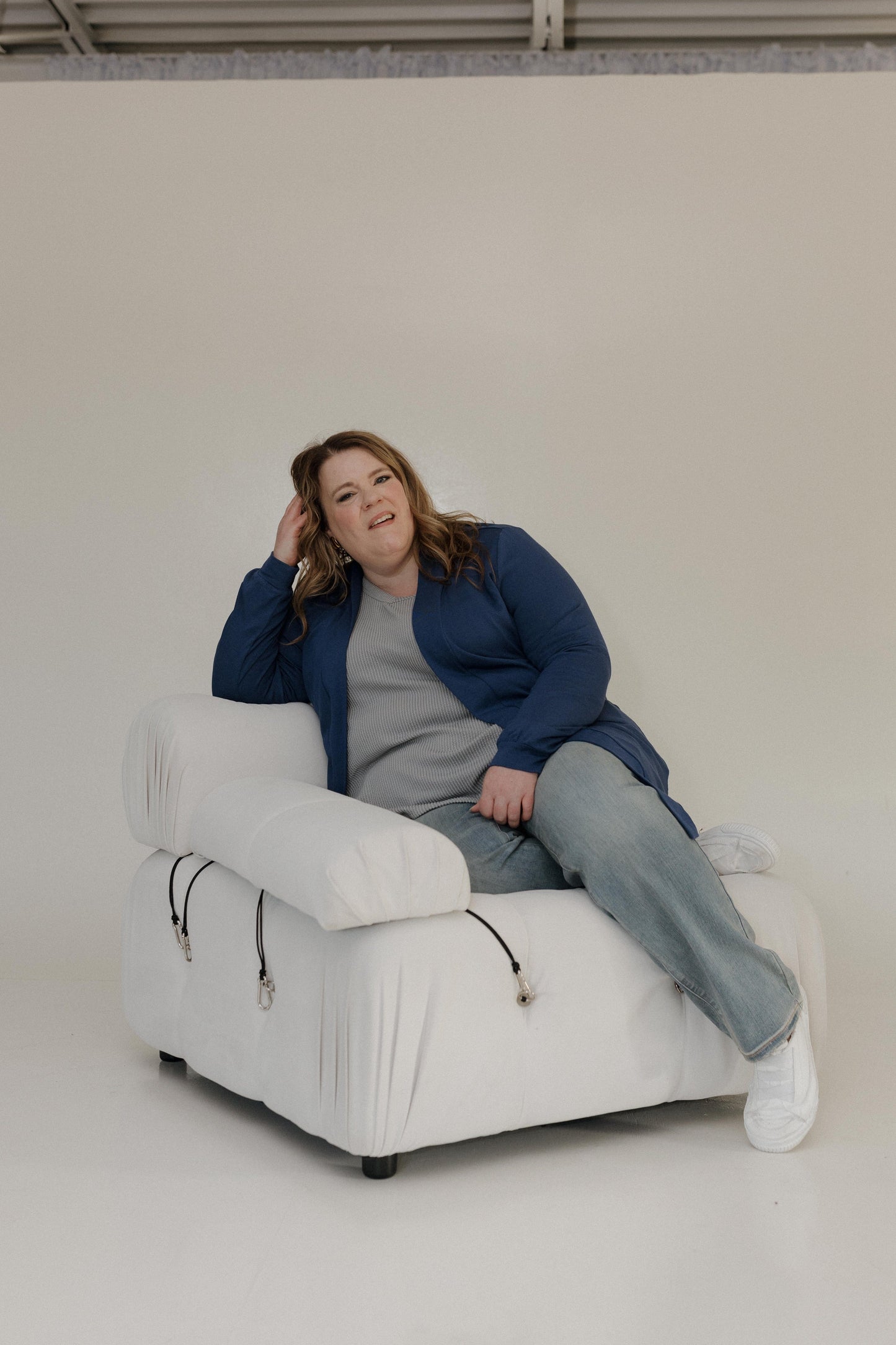 Person sitting on a white chair against a plain background