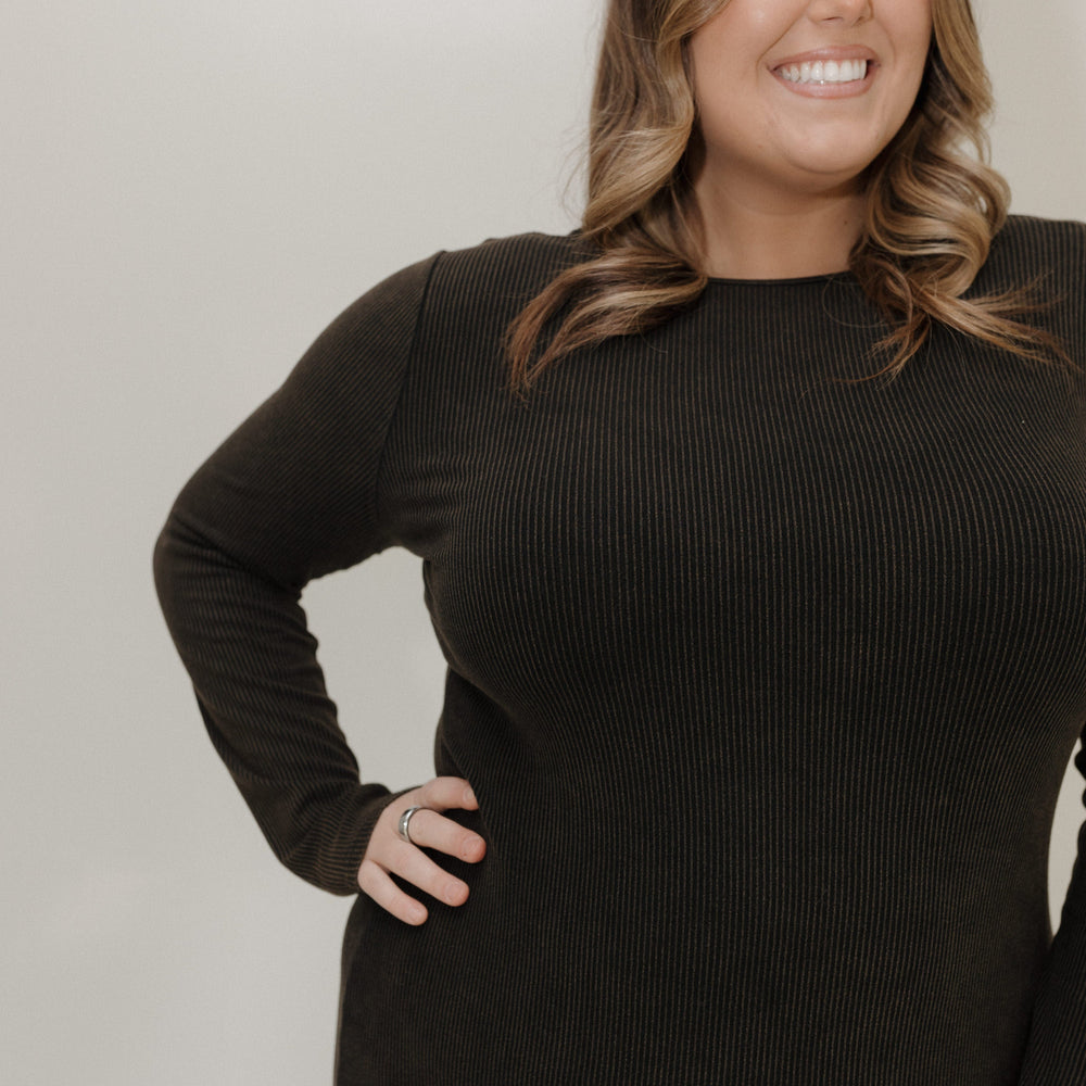 Woman wearing a black ribbed sweater against a plain background