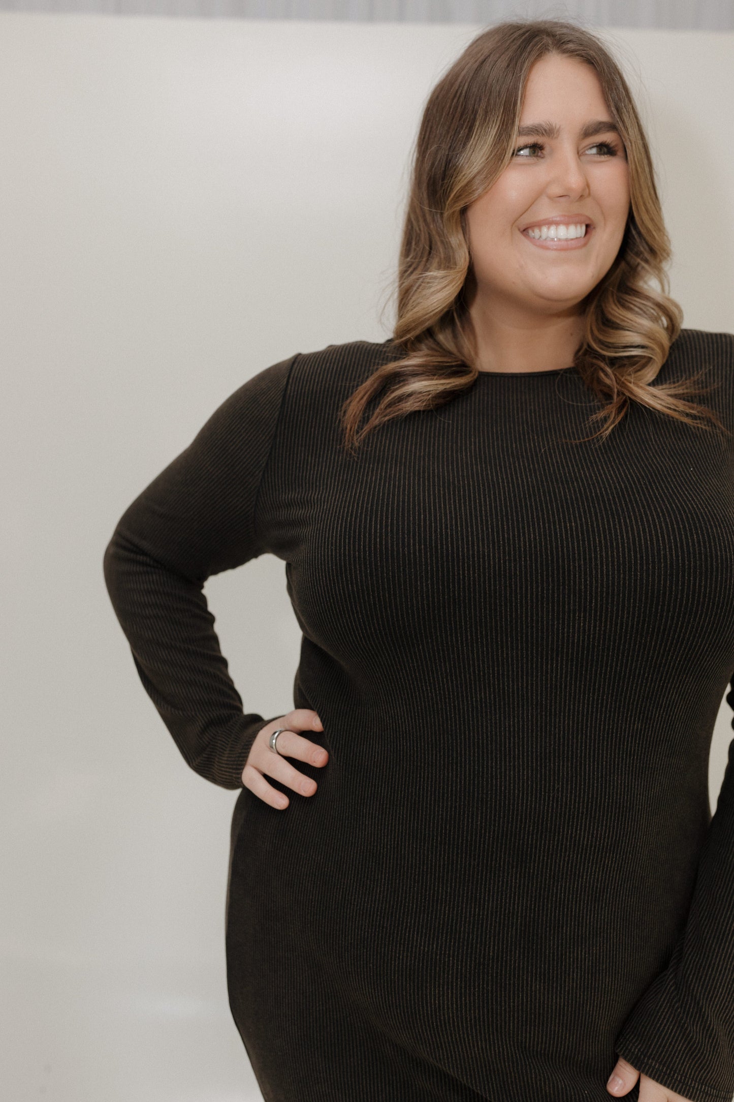 Woman wearing a black ribbed sweater against a plain background