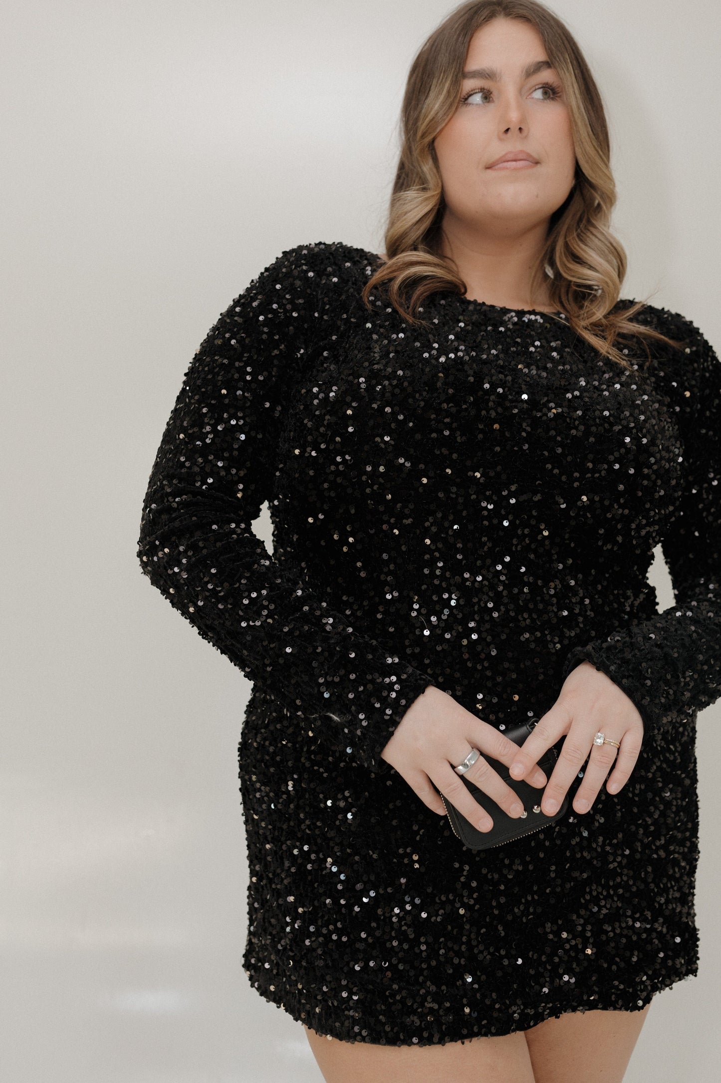 Woman wearing a black sequin dress against a plain background