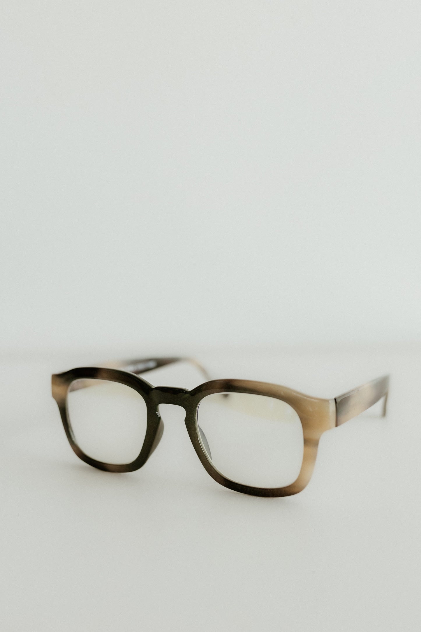 Pair of glasses with a tortoiseshell frame on a light gray background