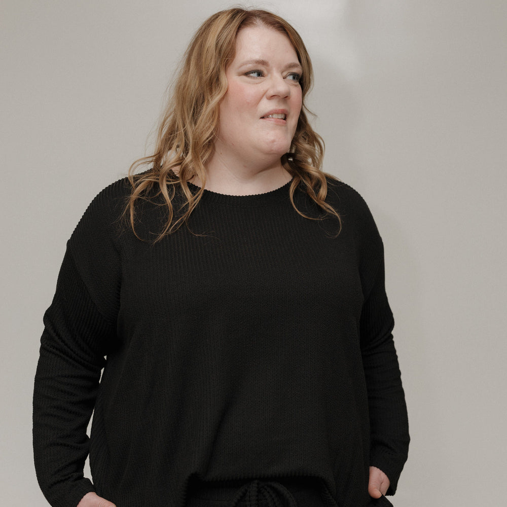 Person wearing a black outfit against a plain background