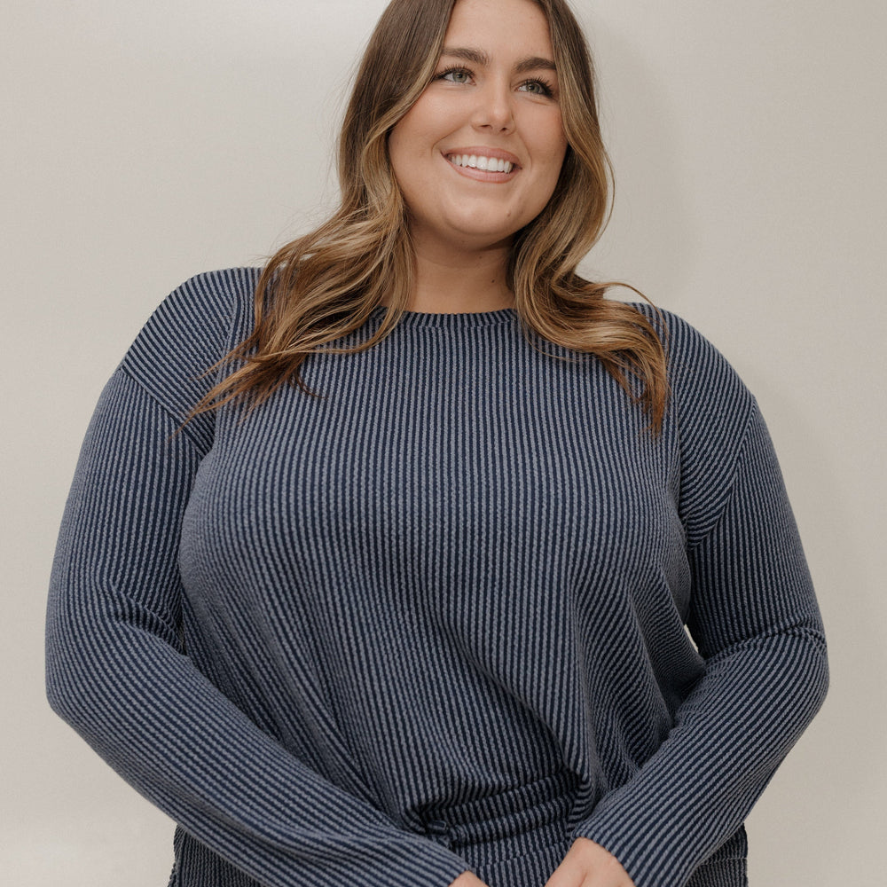 Woman wearing a blue ribbed sweater against a plain background