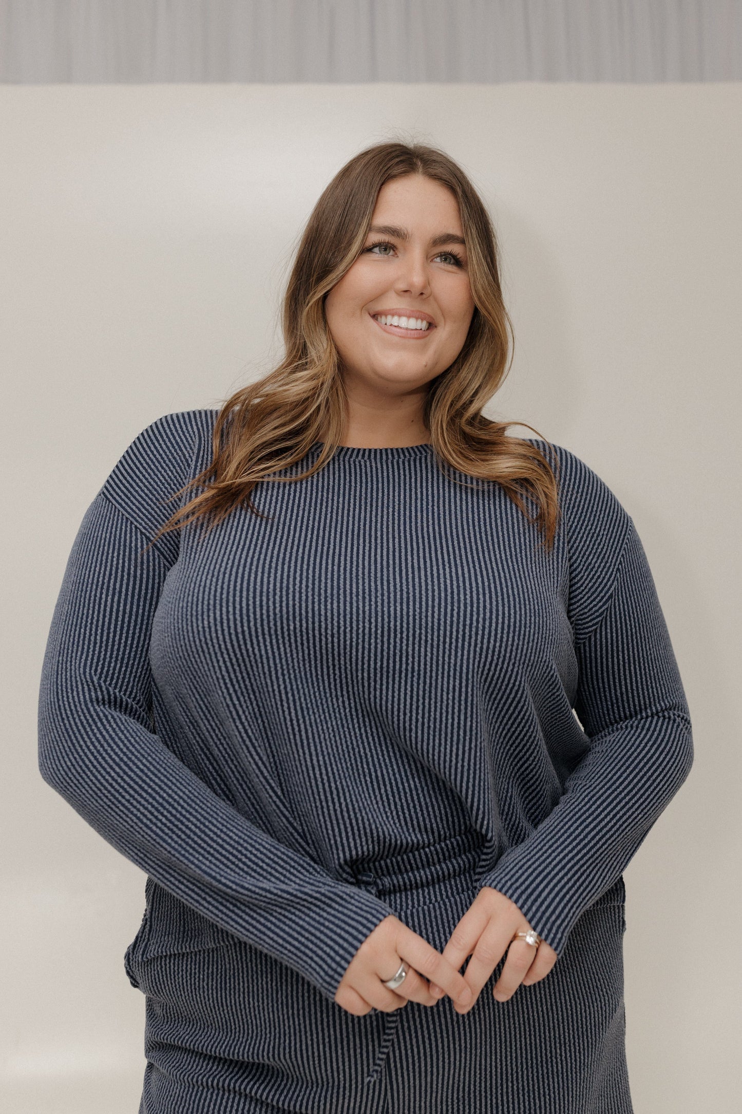 Woman wearing a blue ribbed sweater against a plain background