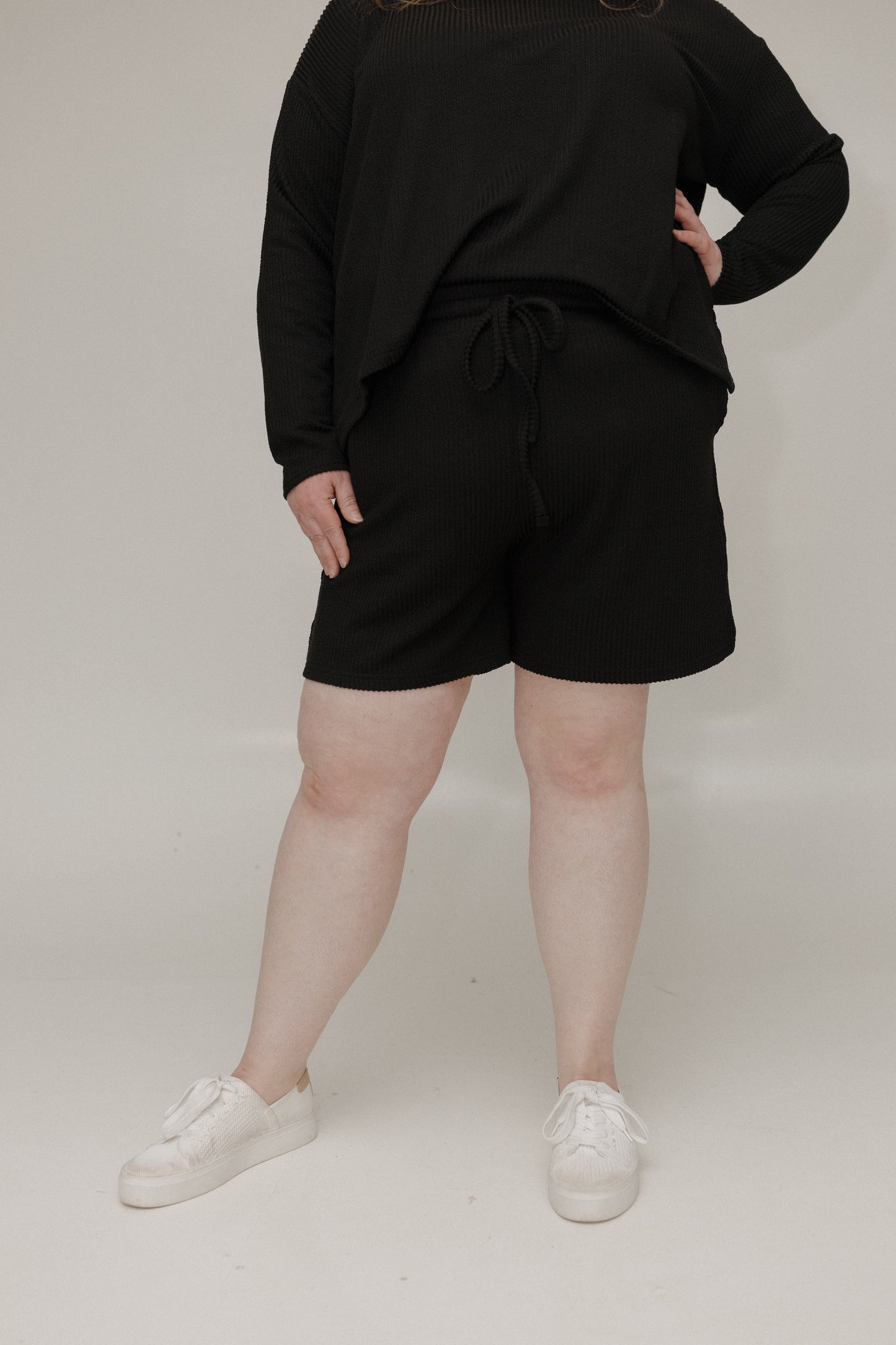 Person wearing a black outfit with shorts on a plain background