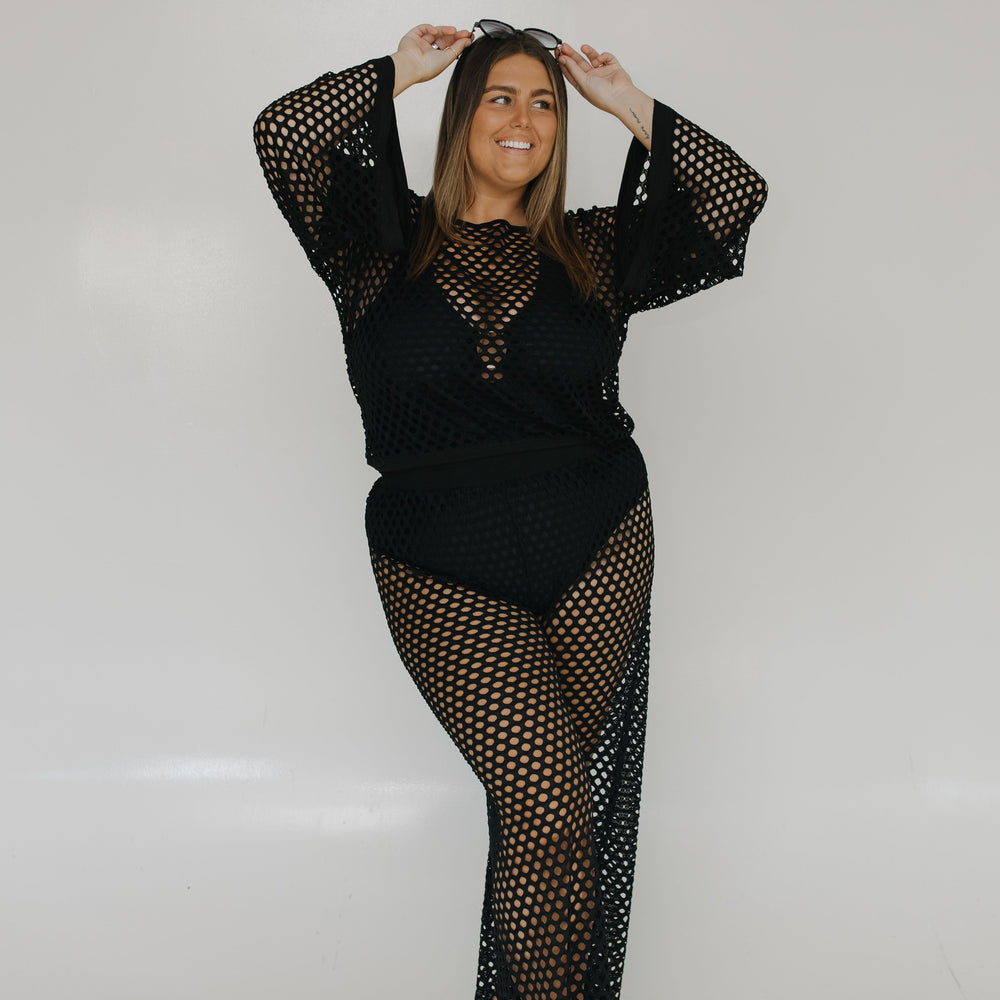 Woman wearing a black fishnet outfit against a white background