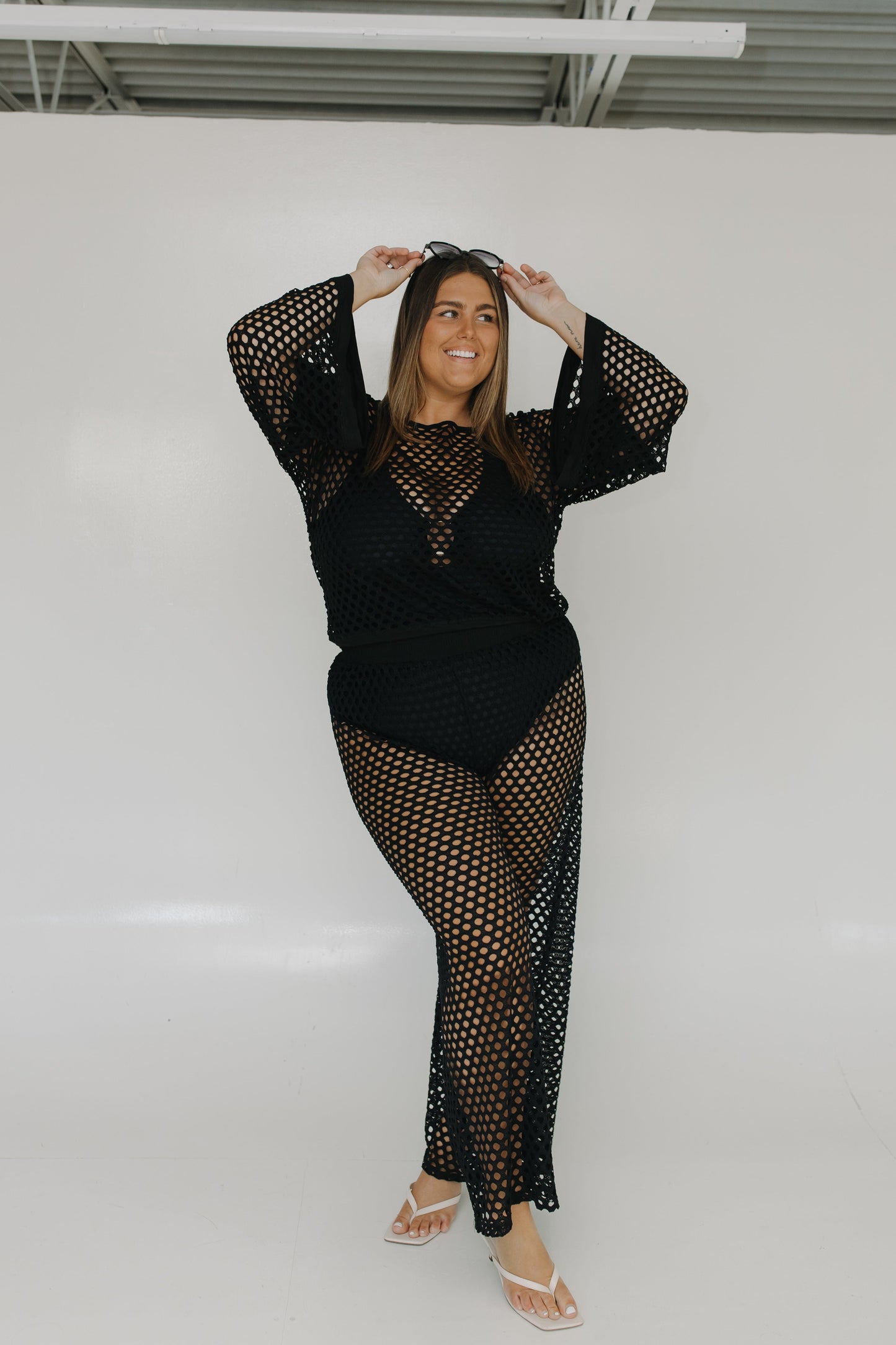 Woman wearing a black fishnet outfit against a white background