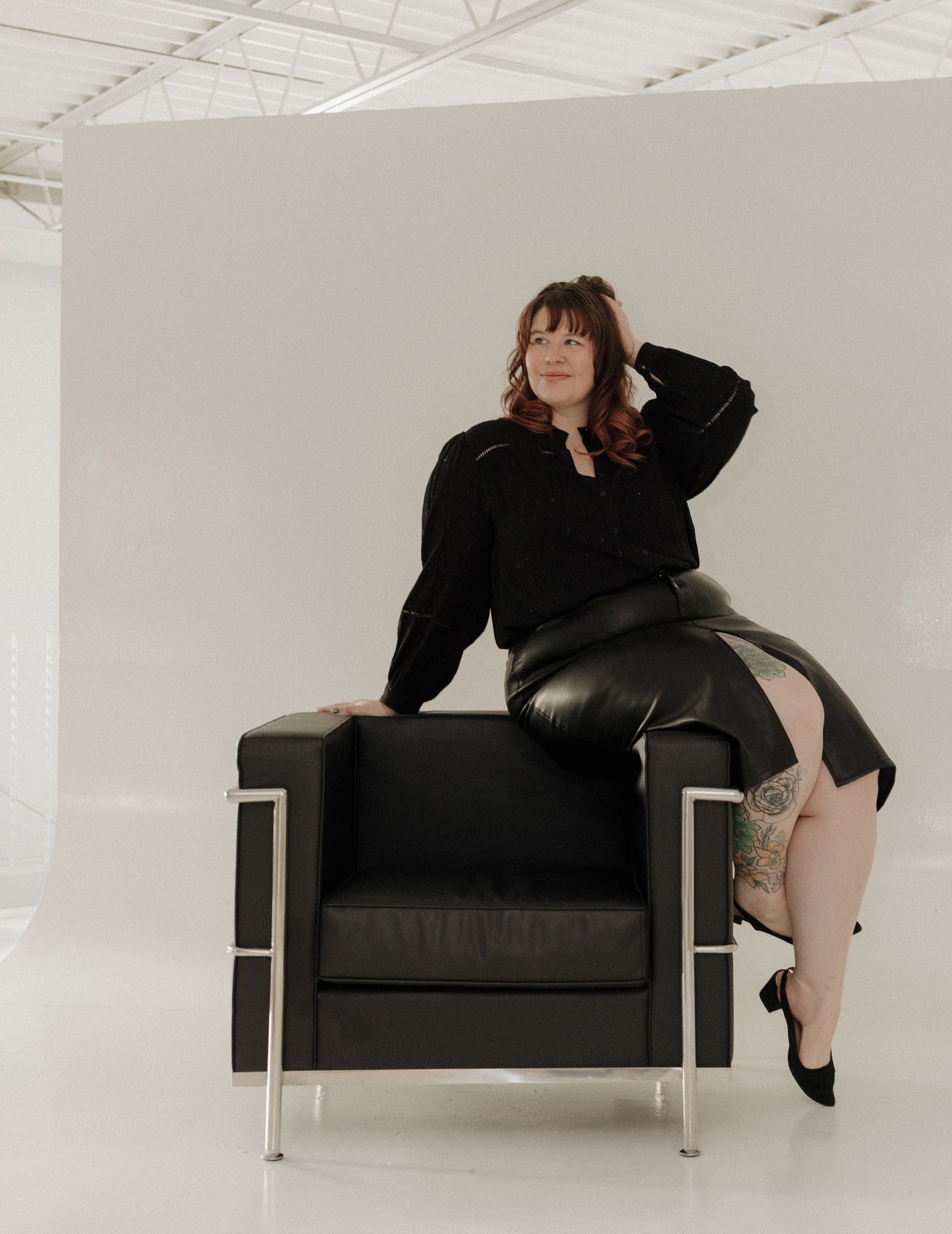 Person sitting on a black chair in a minimal white room