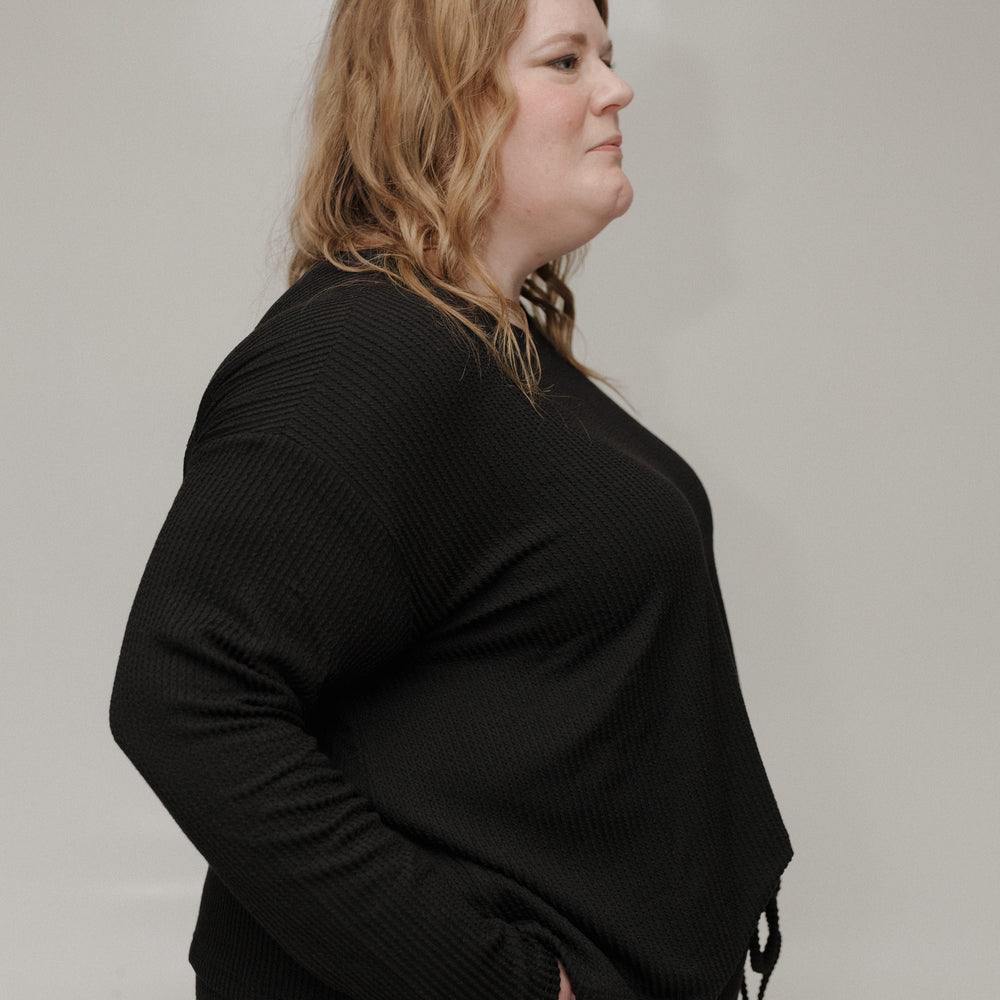 Person wearing a black outfit against a plain background