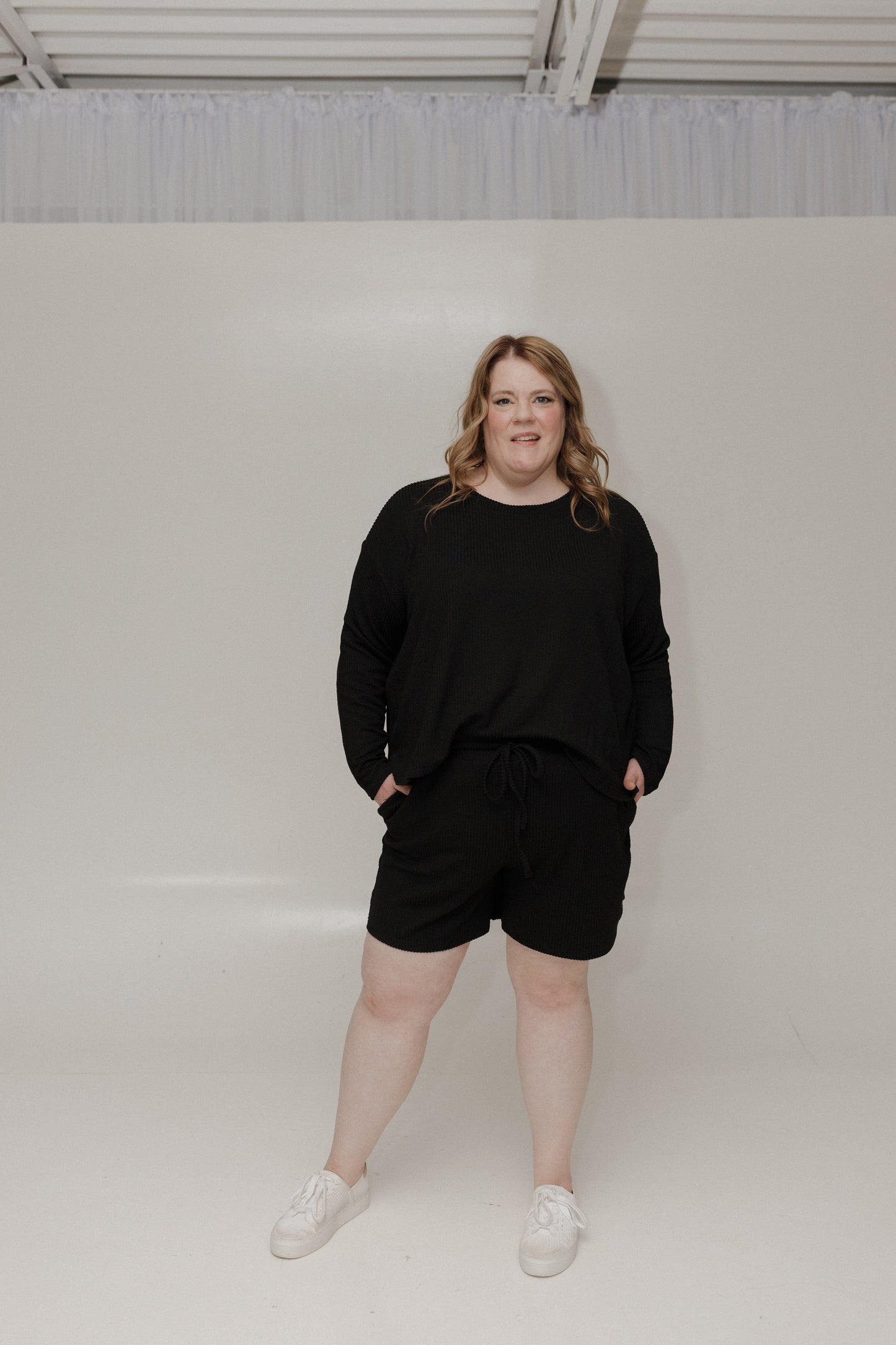 Person wearing a black outfit standing against a white background