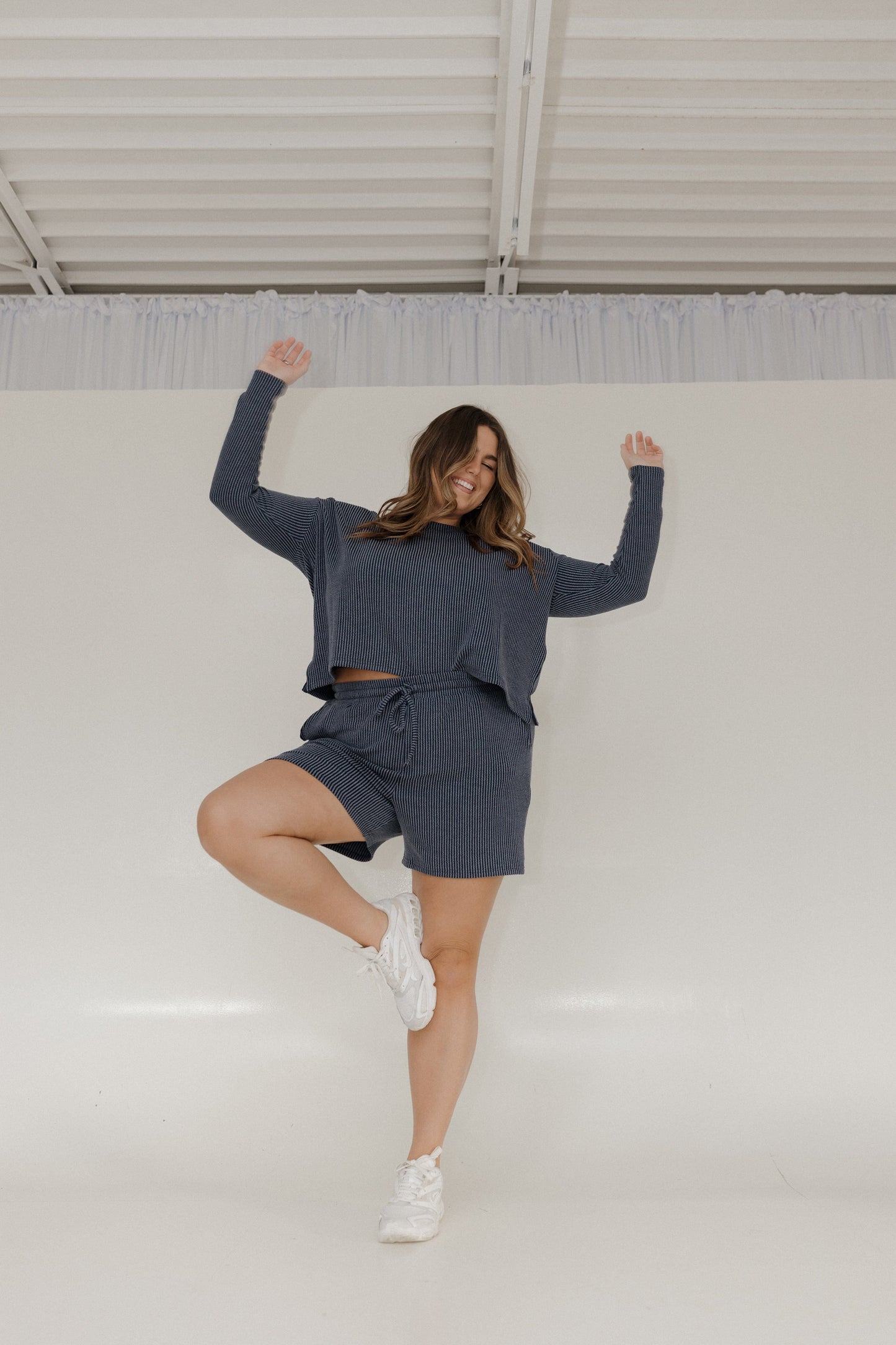 Woman in a blue outfit posing against a white wall