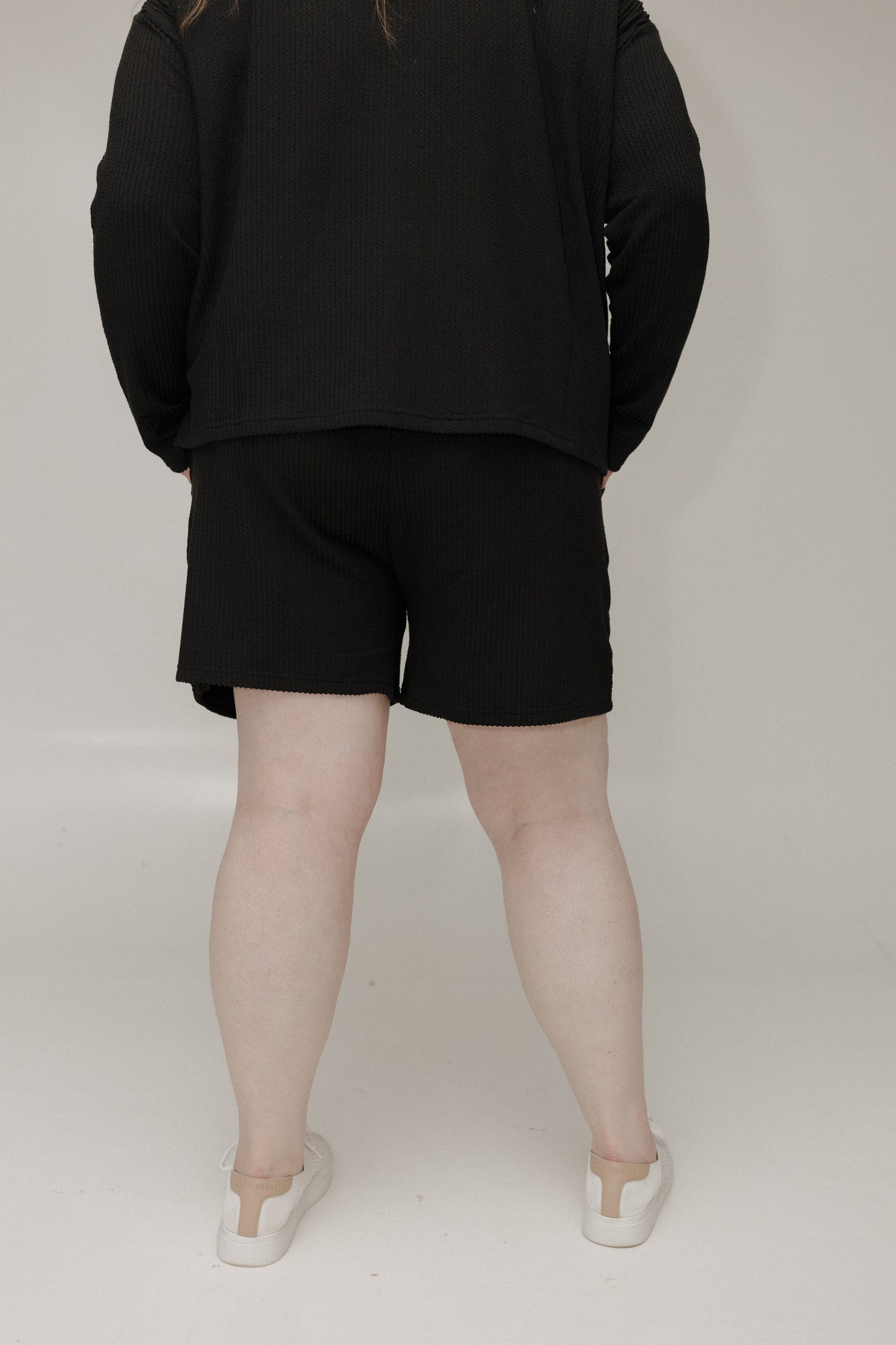 Person wearing a black outfit with shorts on a plain background