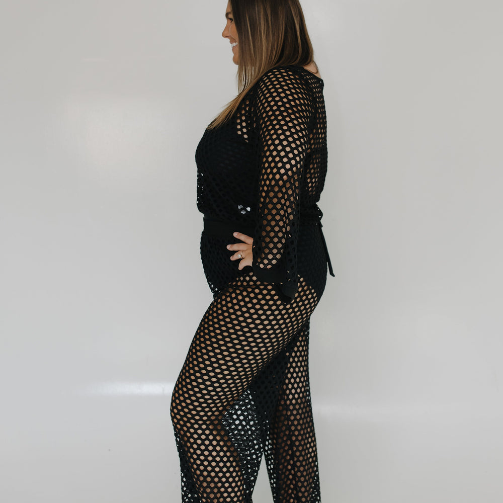 Woman wearing a black fishnet outfit on a white background