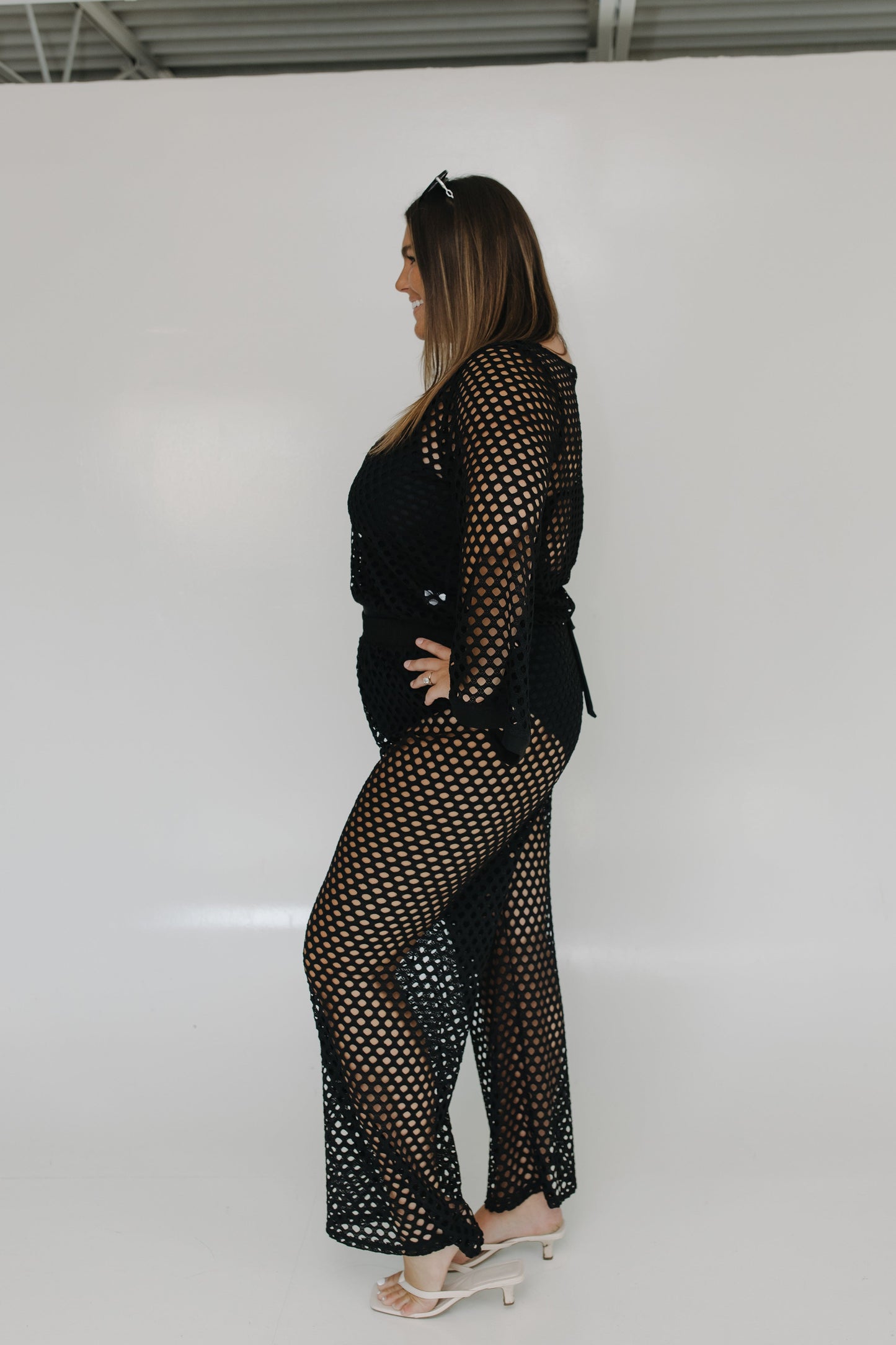 Woman wearing a black fishnet outfit on a white background