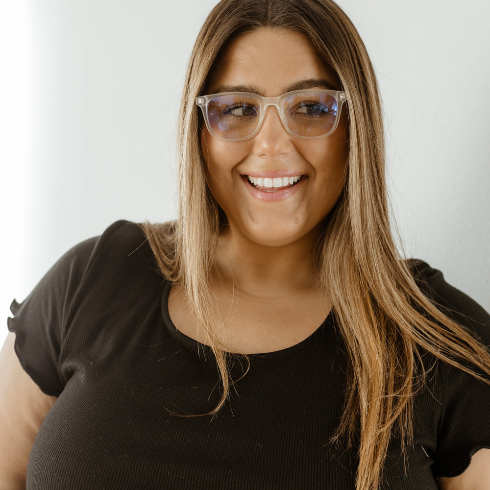 Woman wearing glasses and a black top against a white background
