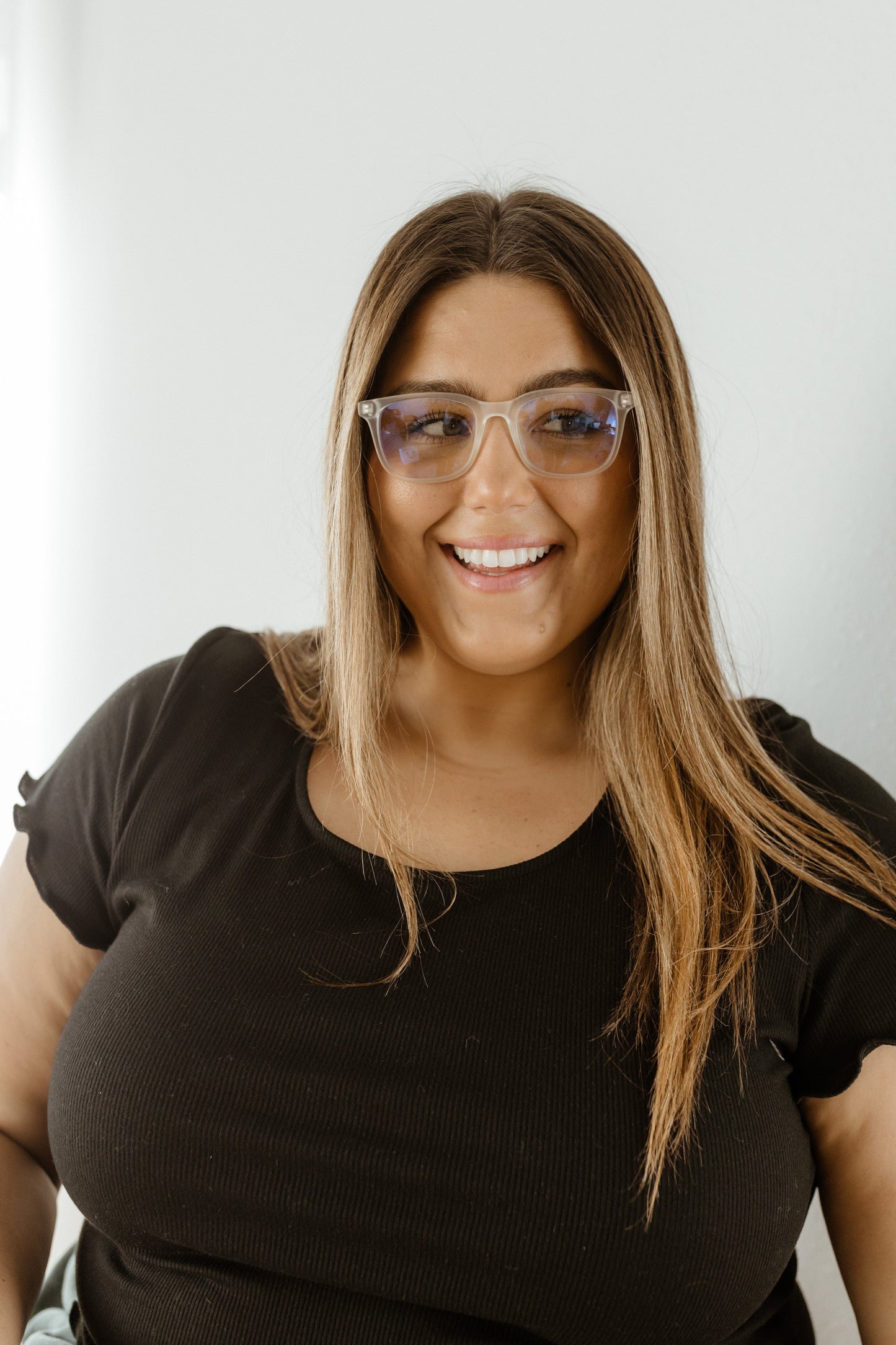 Woman wearing glasses and a black top against a white background