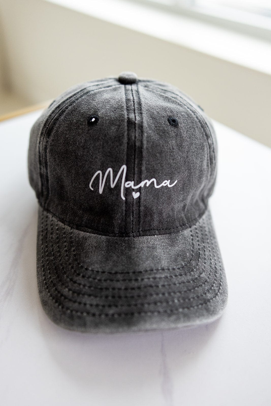 An acid-washed gray baseball cap with "Mama" embroidered in white script on the front is the perfect Mother's Day gifting idea.