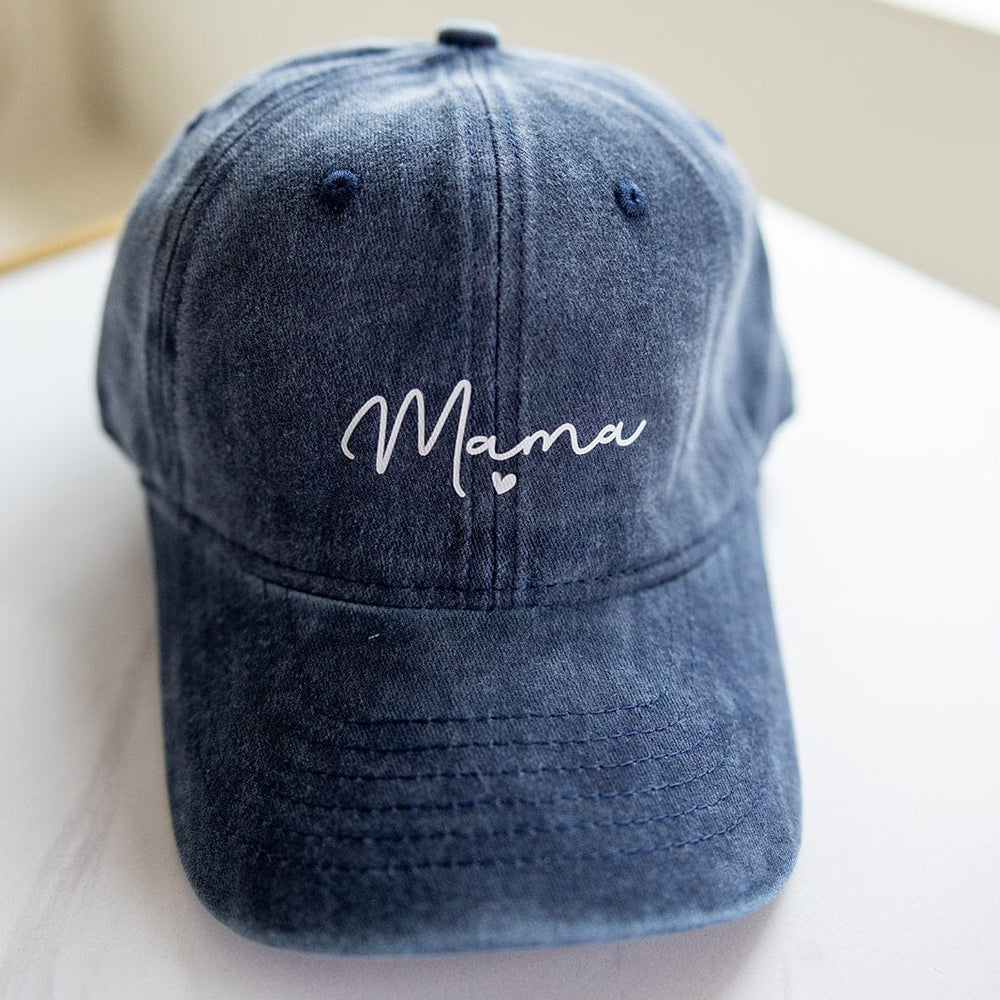 The "MAMA" Acid Washed Baseball Cap in Navy by Love Marlow, with "Mama" elegantly embroidered in white on the front, sits stylishly on a light surface—making it the perfect Mother's Day gift to add a special touch of love.