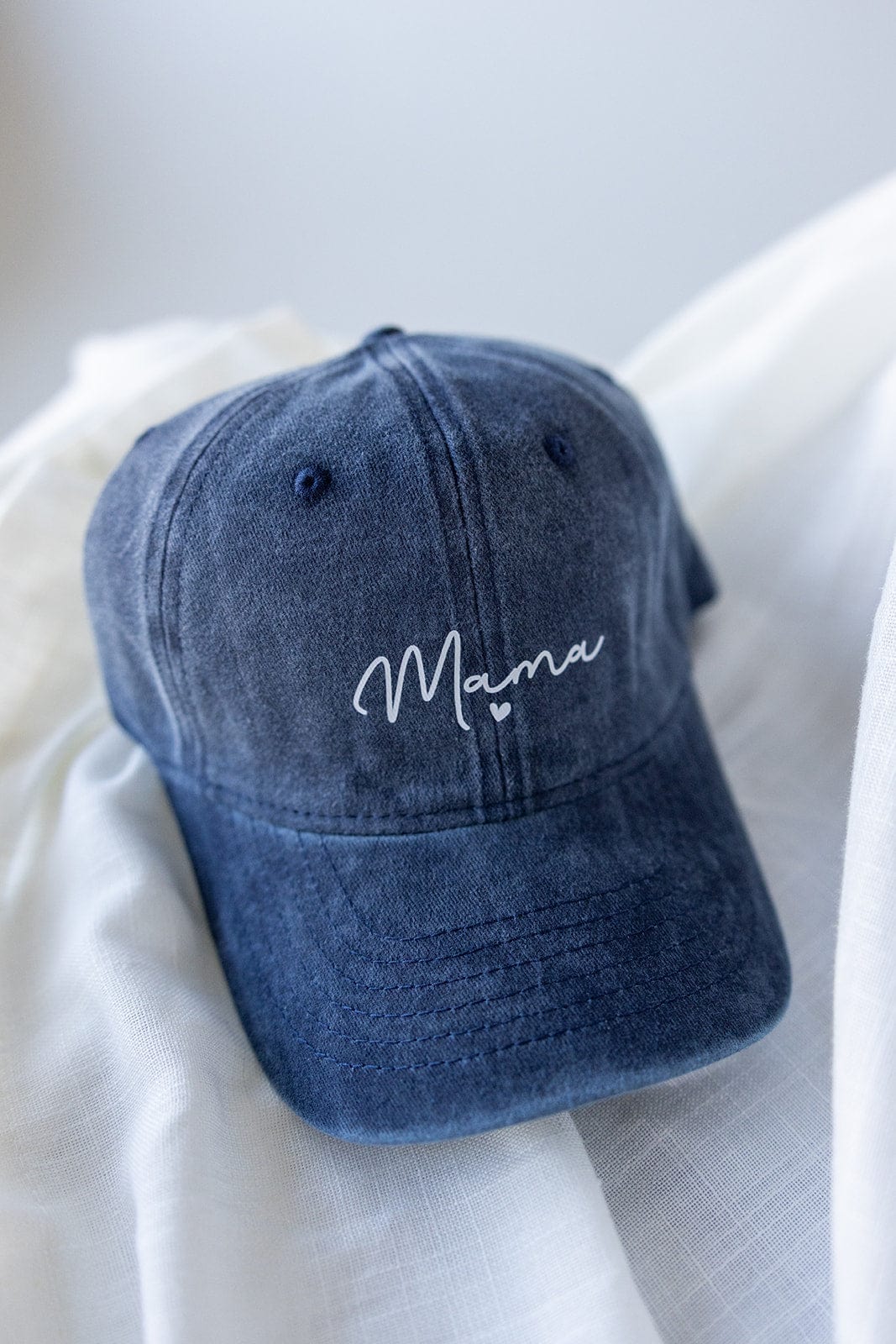 This Love Marlow cap, named "MAMA" Acid Washed Baseball Cap in Navy, features an acid-washed design with "Mama" elegantly scripted in white on the front.