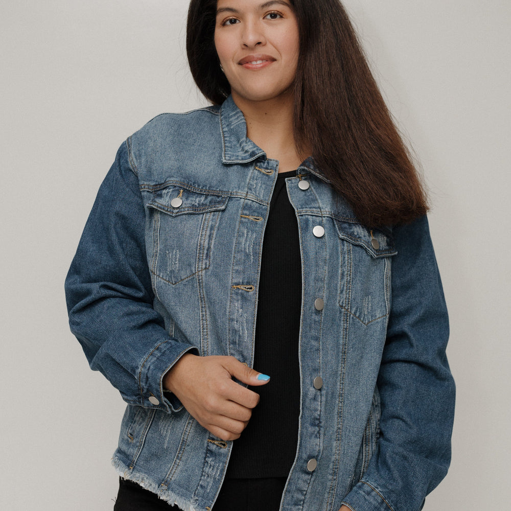 Person wearing a denim jacket against a plain background