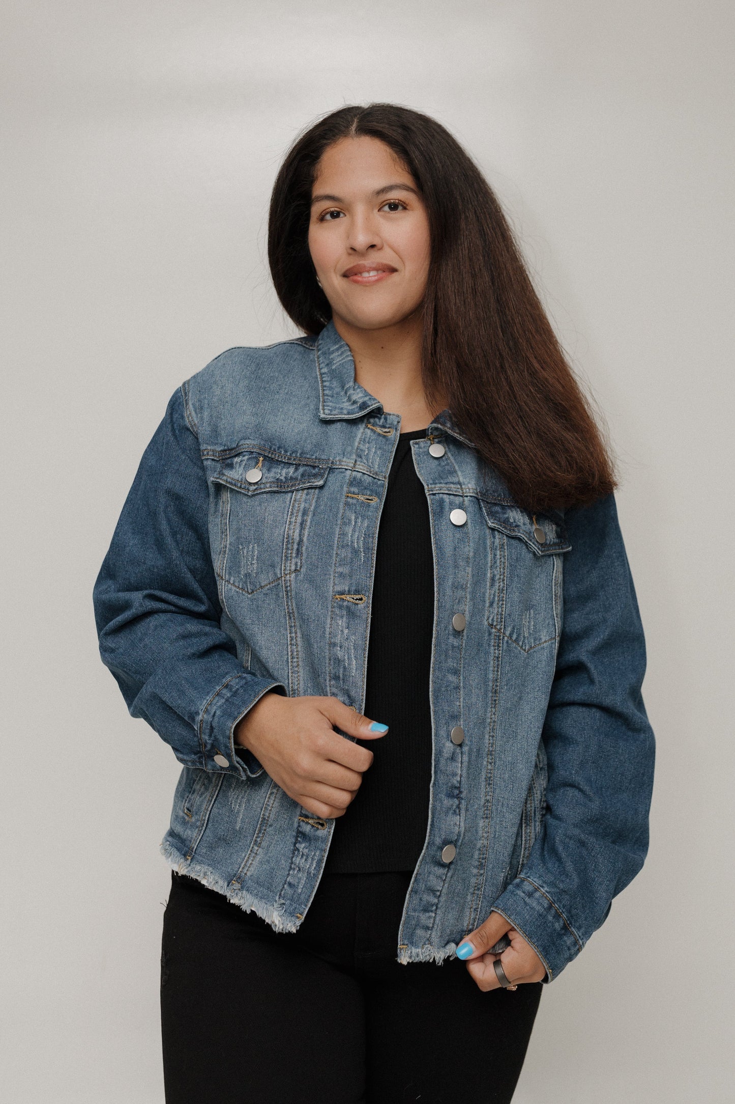Person wearing a denim jacket against a plain background