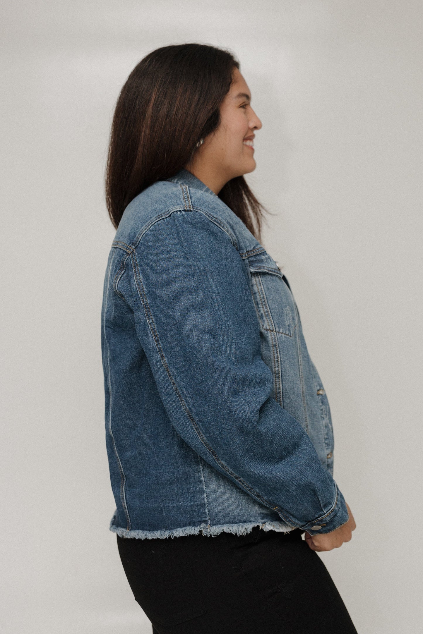 Person wearing a denim jacket on a plain background