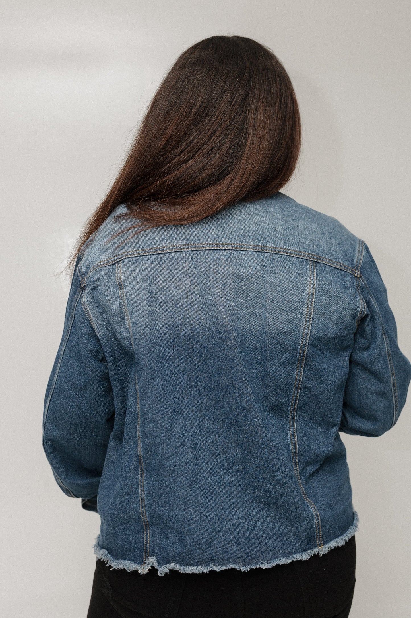 Person wearing a blue denim jacket against a plain background