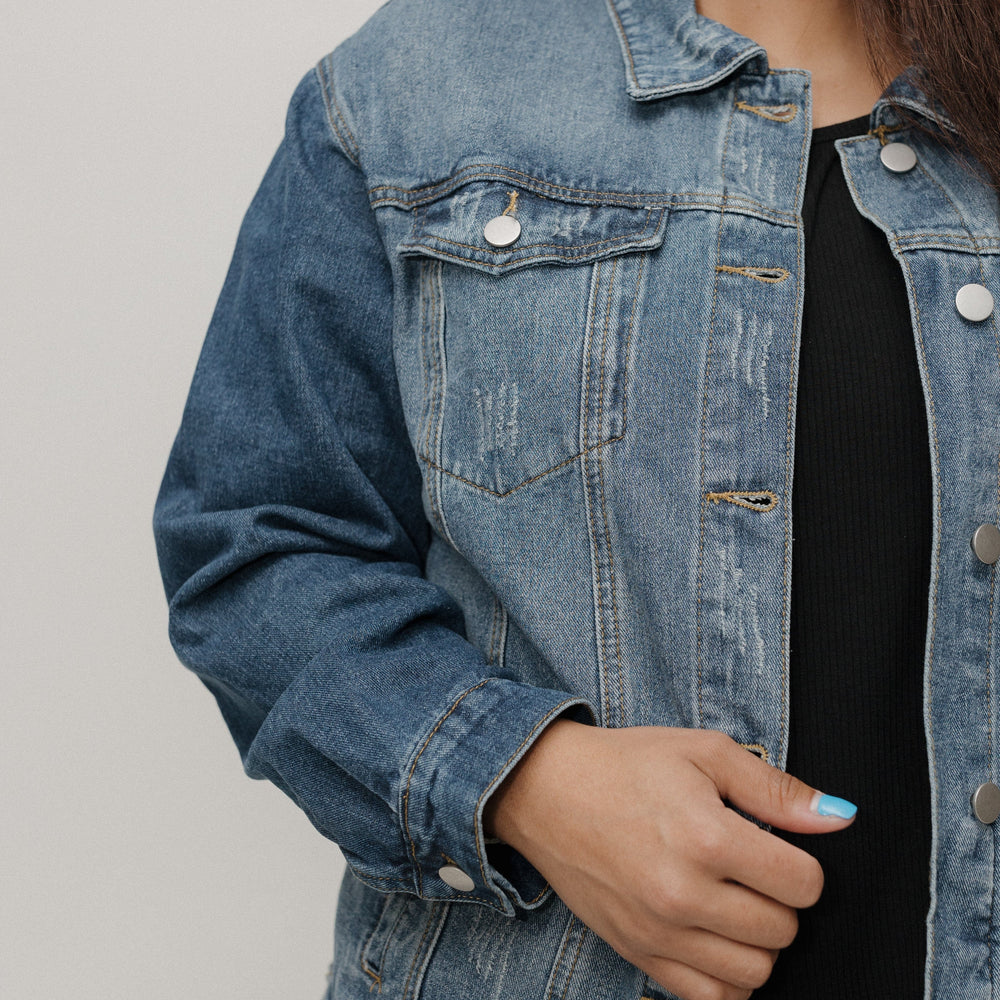 Person wearing a denim jacket against a plain background