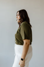 A person with shoulder-length dark hair stands with their back to the camera, wearing a festive Christmas tee and a white skirt, capturing the holiday spirit.