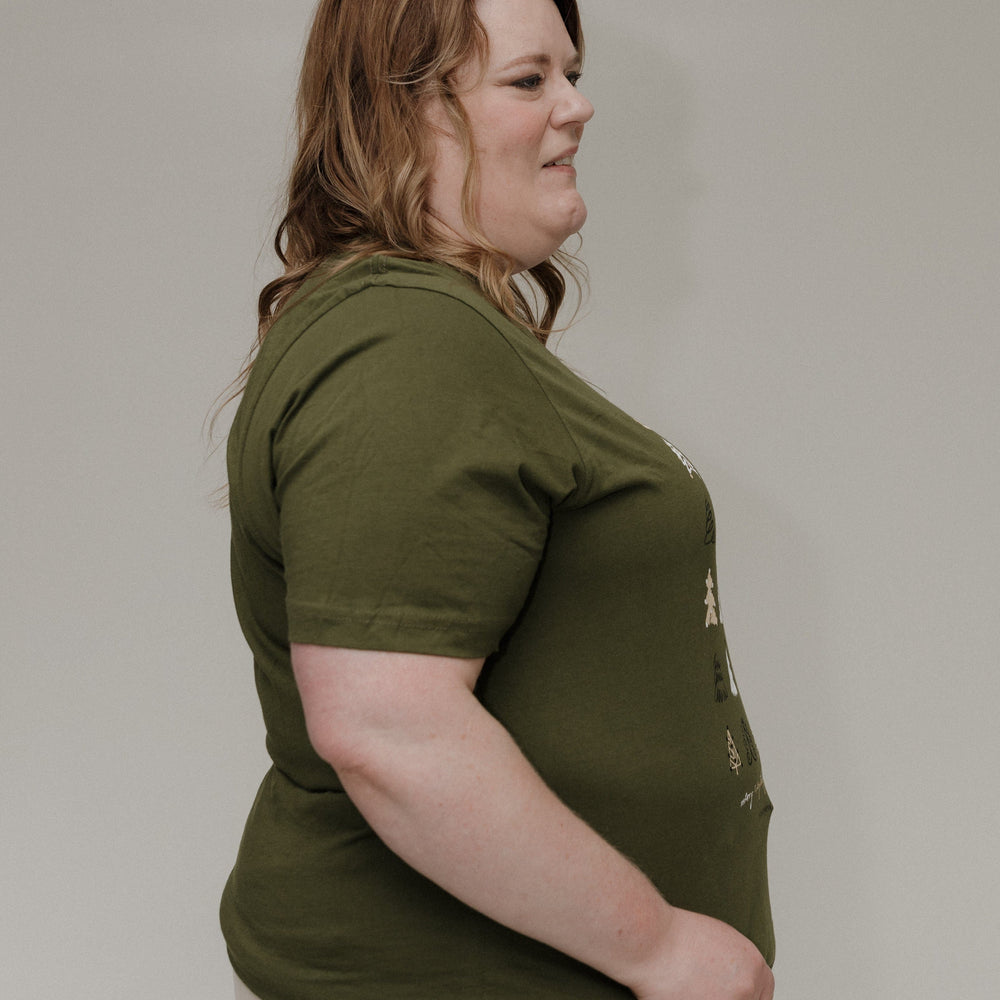 Person wearing a green t-shirt and beige pants against a plain background