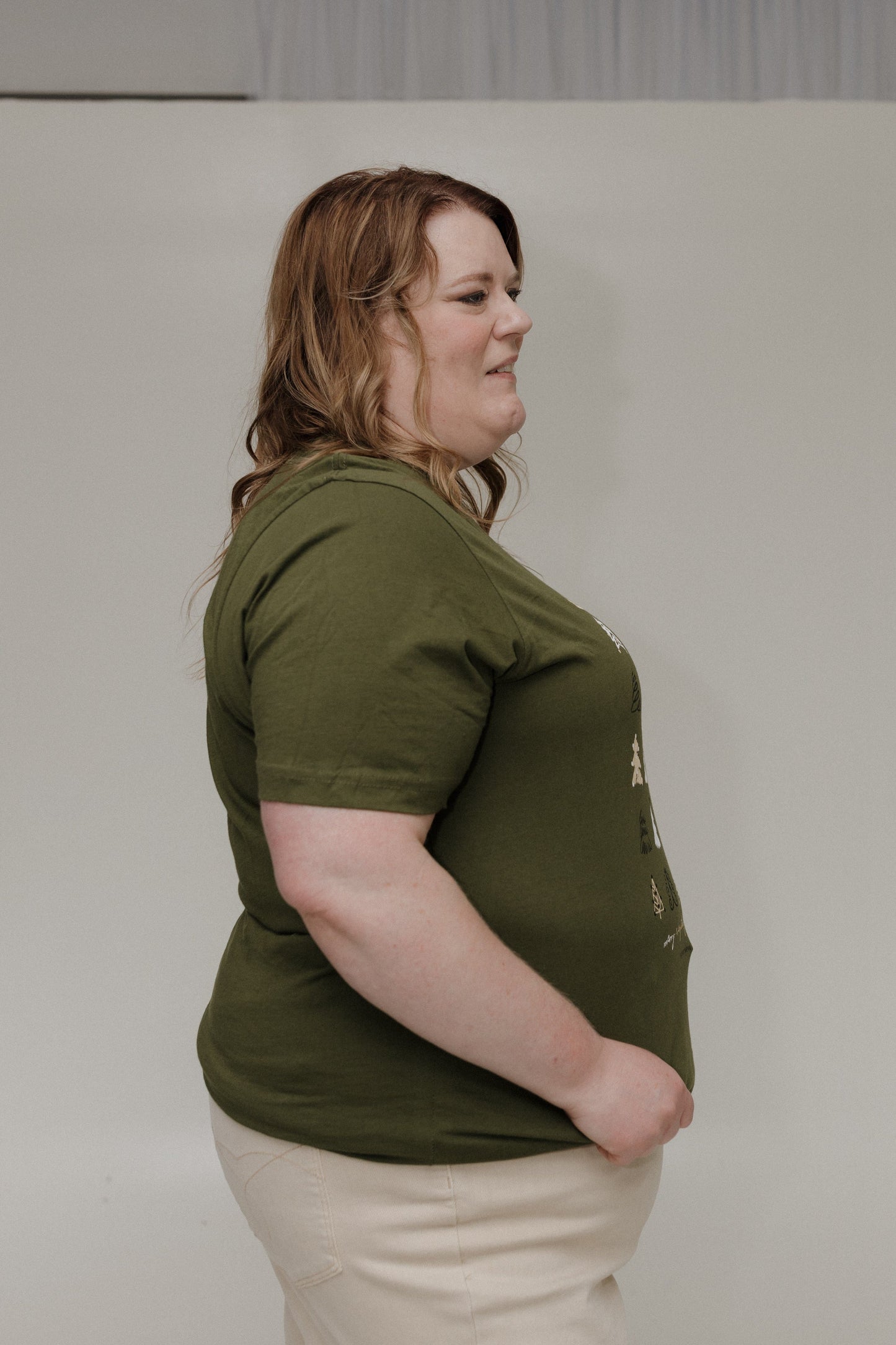 Person wearing a green t-shirt and beige pants against a plain background