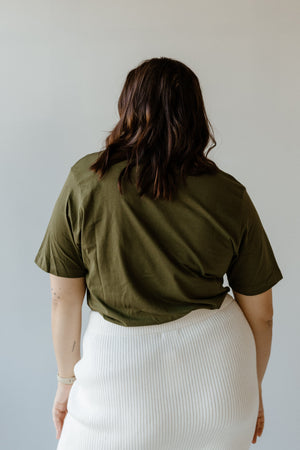 A person with shoulder-length dark hair stands with their back to the camera, wearing a festive Christmas tee and a white skirt, capturing the holiday spirit.